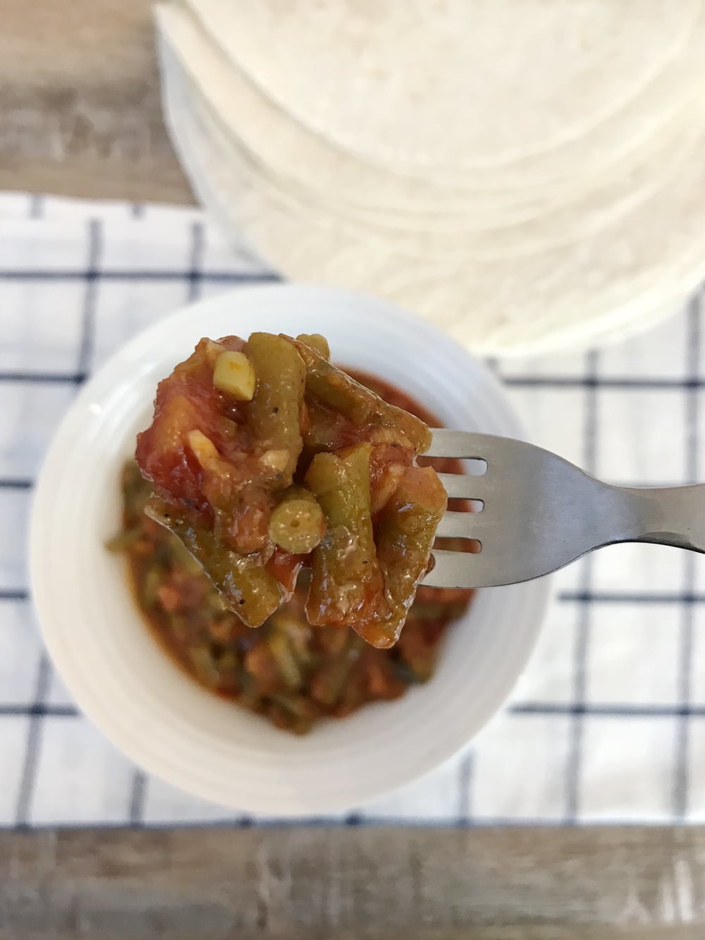 a spoonful of green beans in tomato sauce.