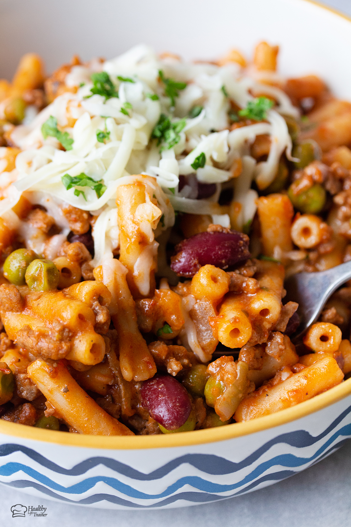 Beef Mac And Cheese in a bowl topped with more cheese.