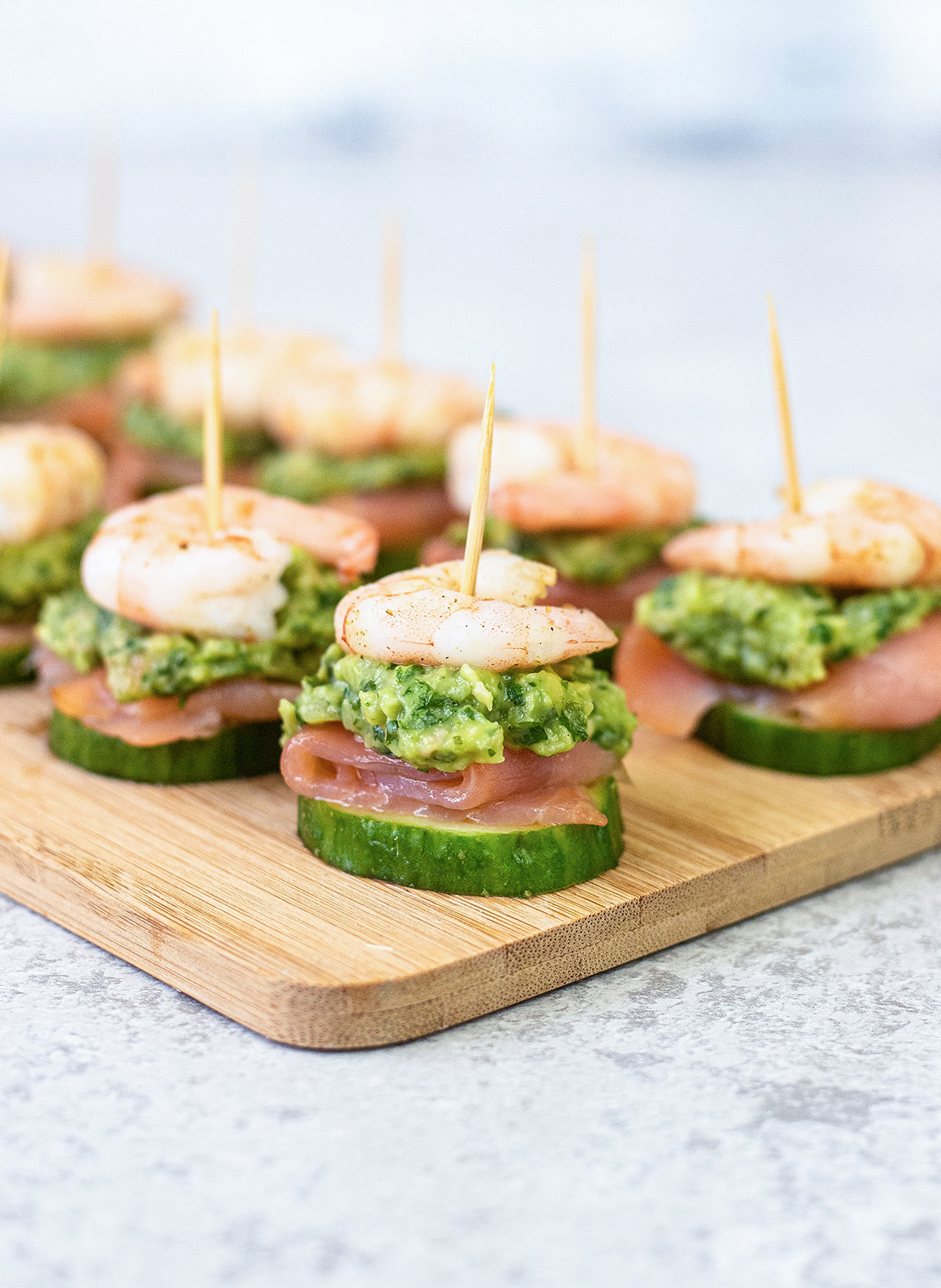 shrimp over creamy guacamole on a piece of smoked salmon and a crunchy slice of cucumber.