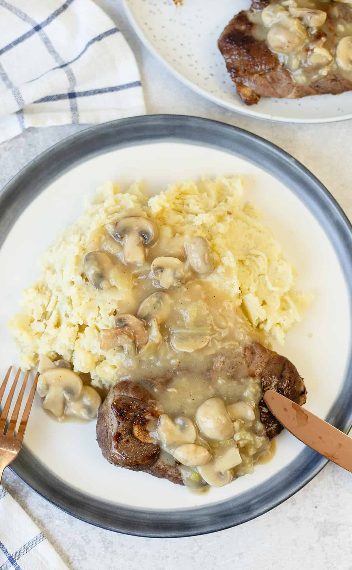 Steaks with Mushroom Gravy and mashed potatoes in a plate.