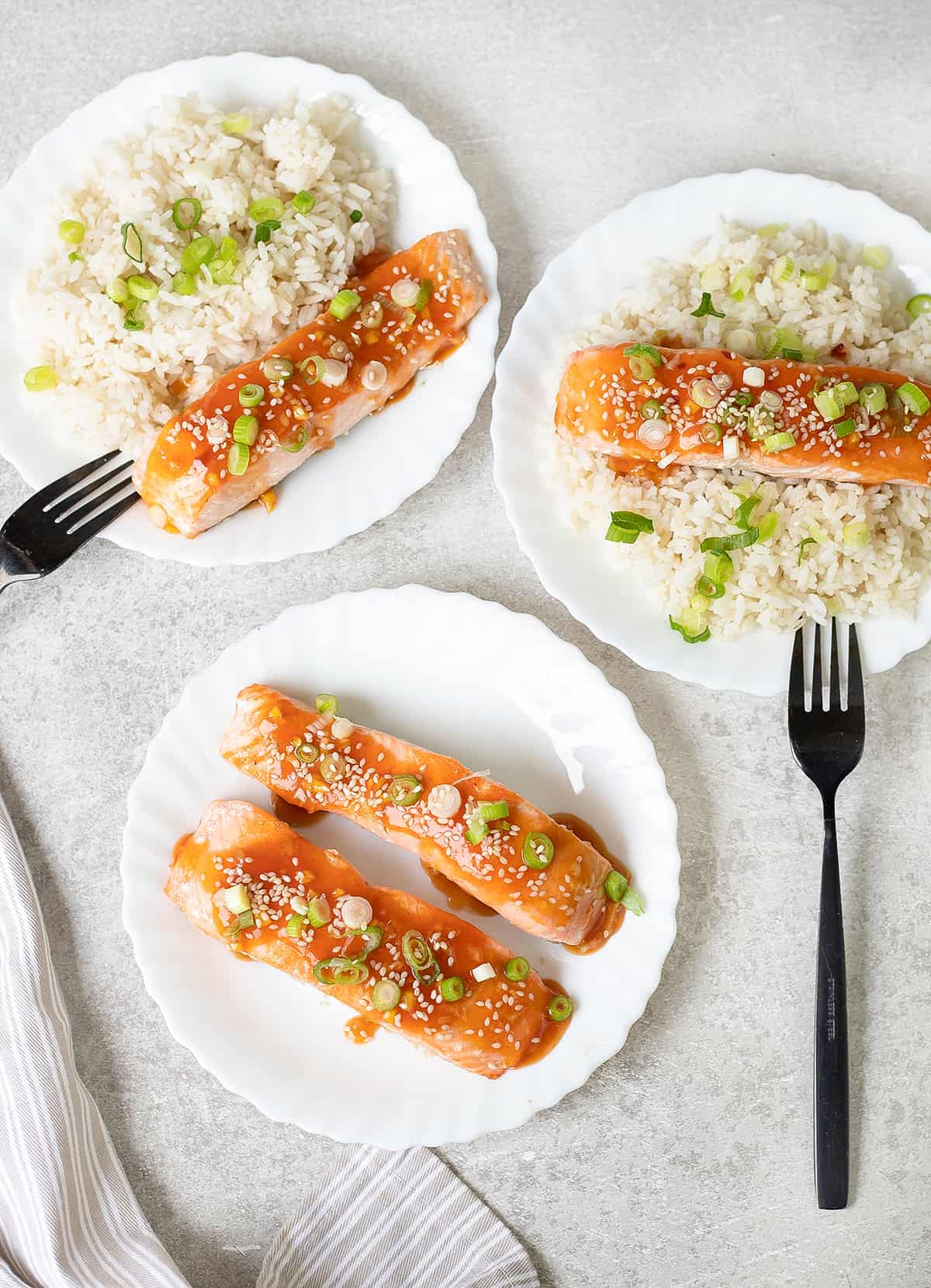 Three plates of white rice topped with Sweet And Sour Salmon.