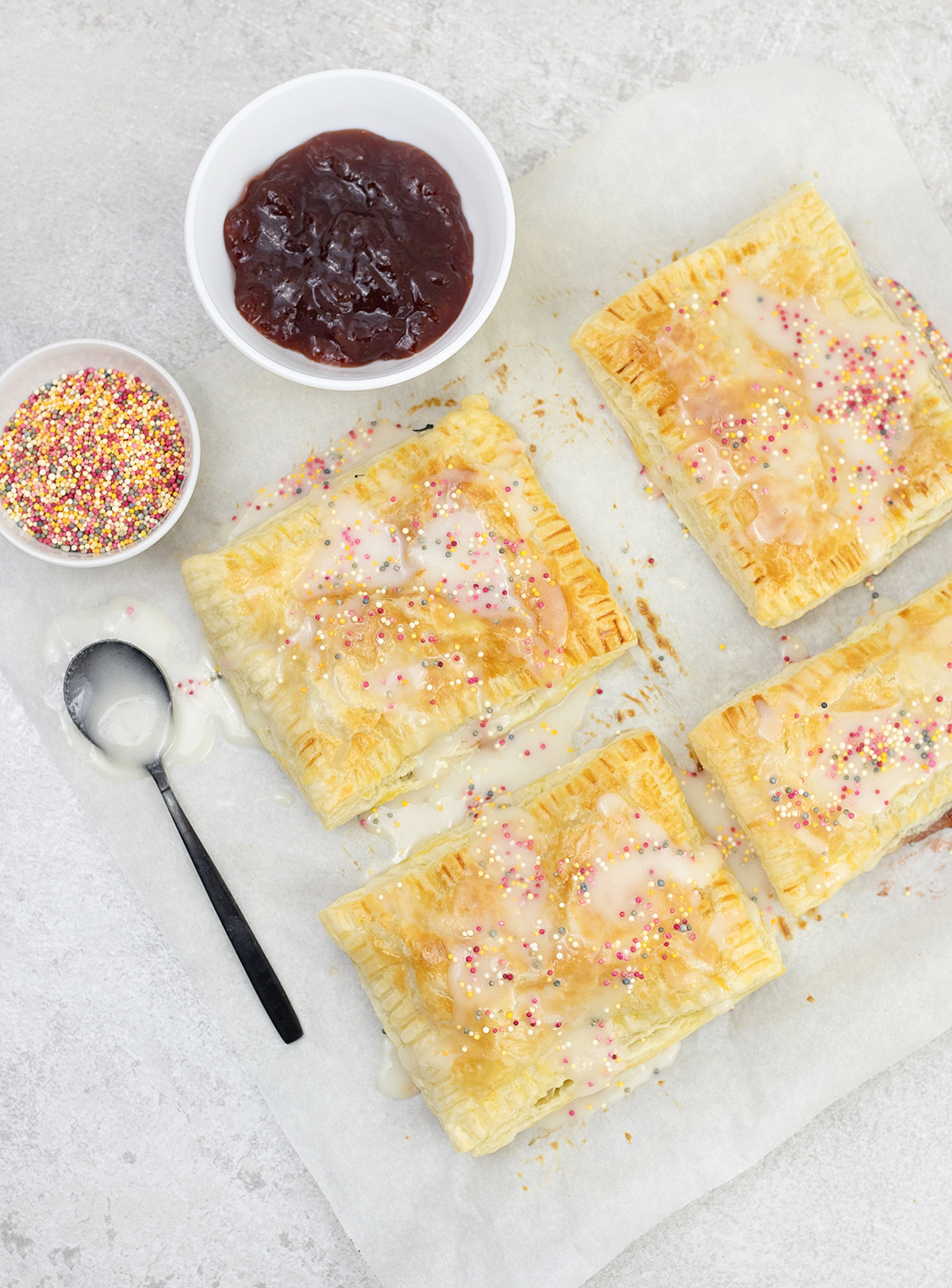 homemade puff pastry pop tarts and a bowl of strawberry jam.