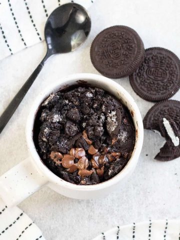 Oreo microwave mug cake and some Oreos are next to it.