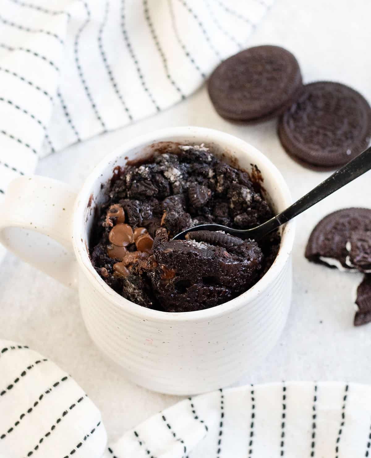 Oreo microwave mug cake and some Oreos are next to it.