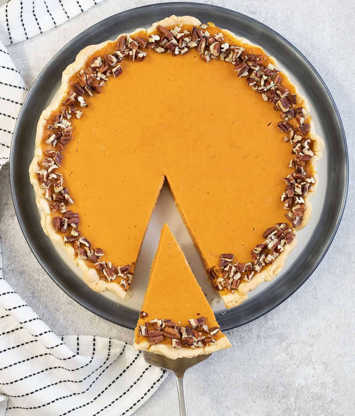 A whole pumpkin custard pie topped with chopped pecans.