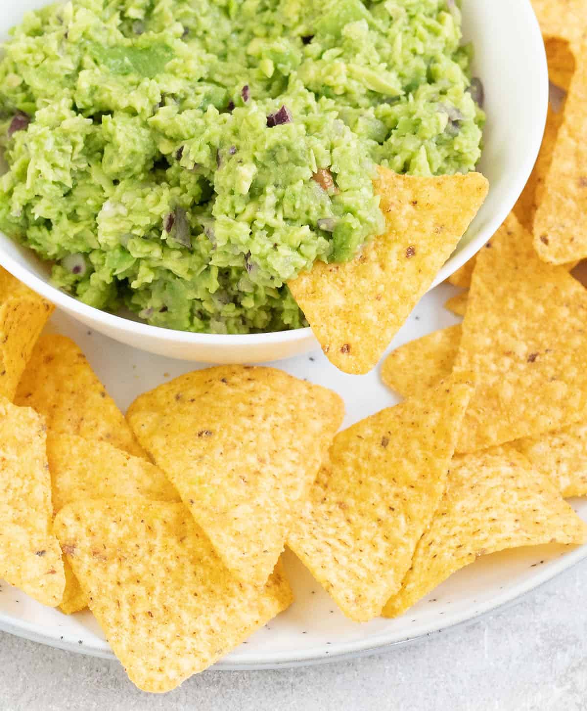 Guacamole in a big bowl and a tortilla chips 