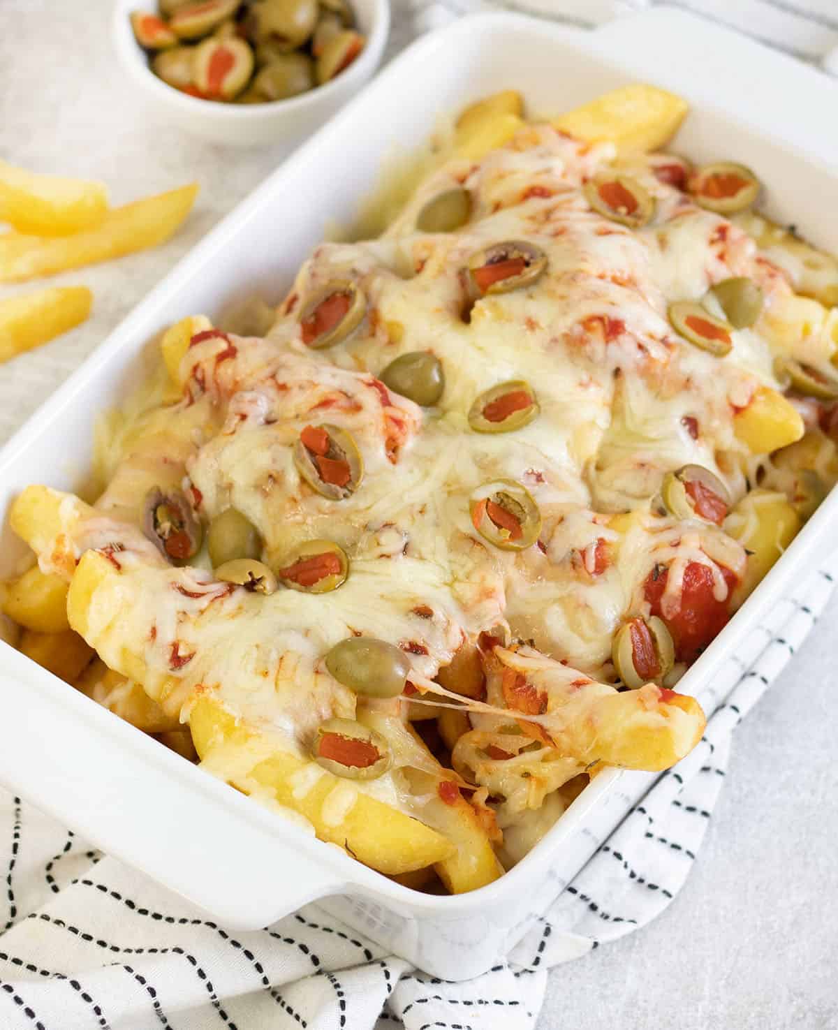a baking dish loaded with Pizza Fries.