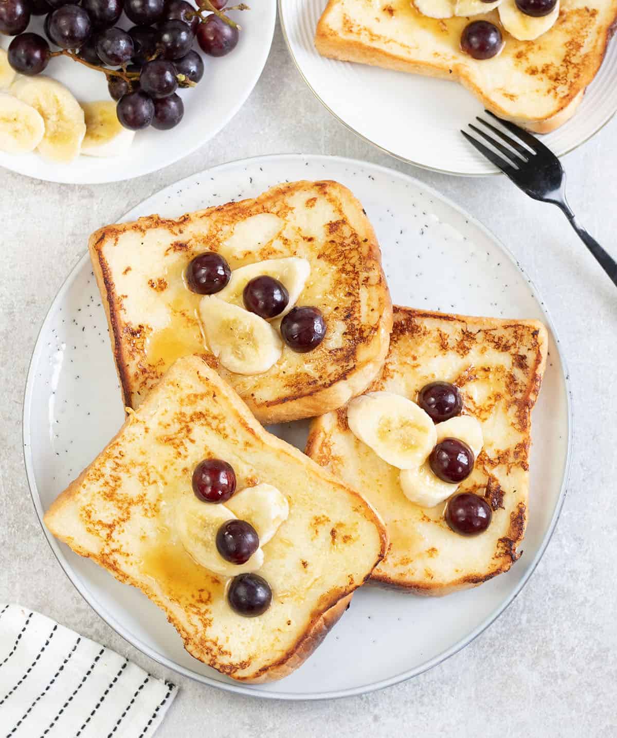 Buttermilk French Toast in a plate topped with grapes and bananas