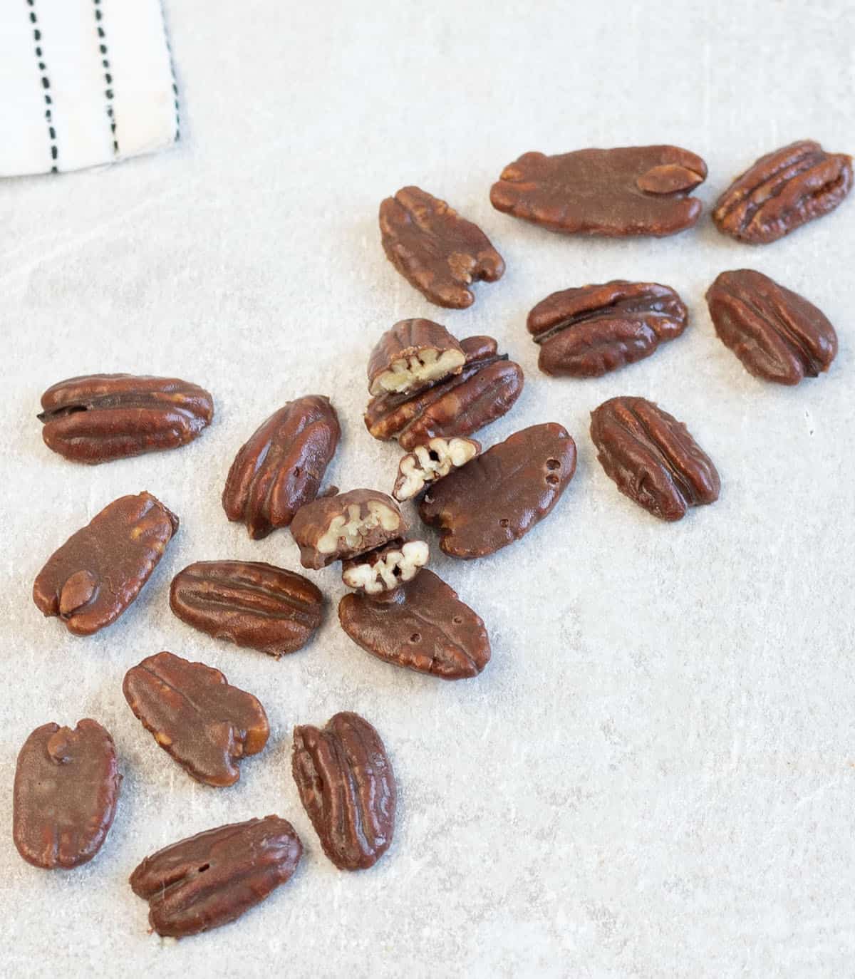 Chocolate Covered Pecans cut into halves and scattered on the table.