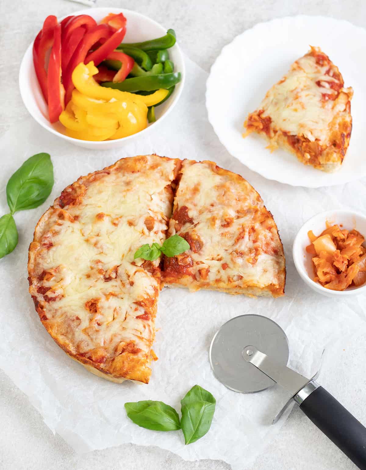 Kimchi Pizza topped with fresh basil, bowl of veggies.