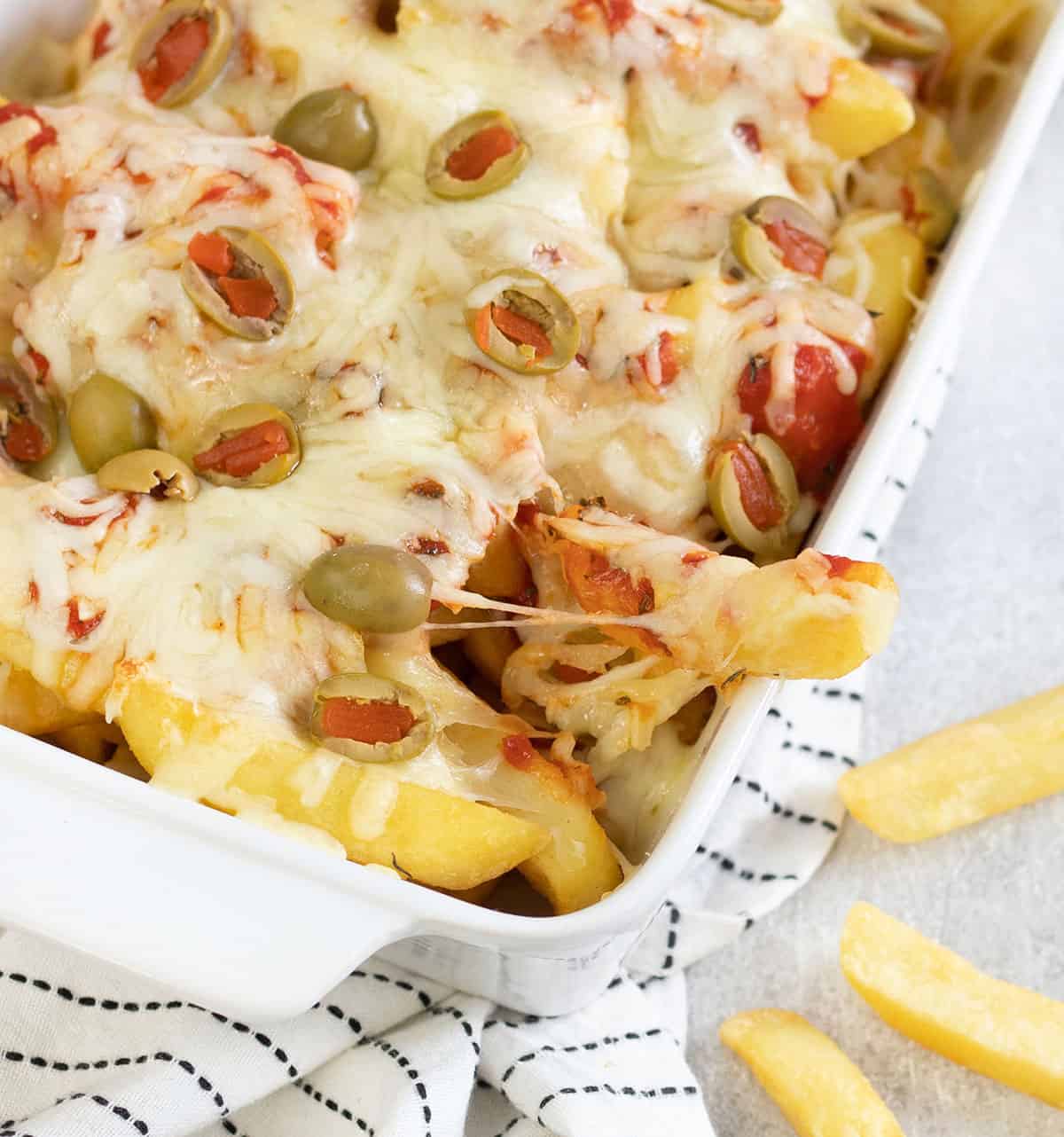 Some pizza fries are being taken from a tray, and the cheese is stretching.