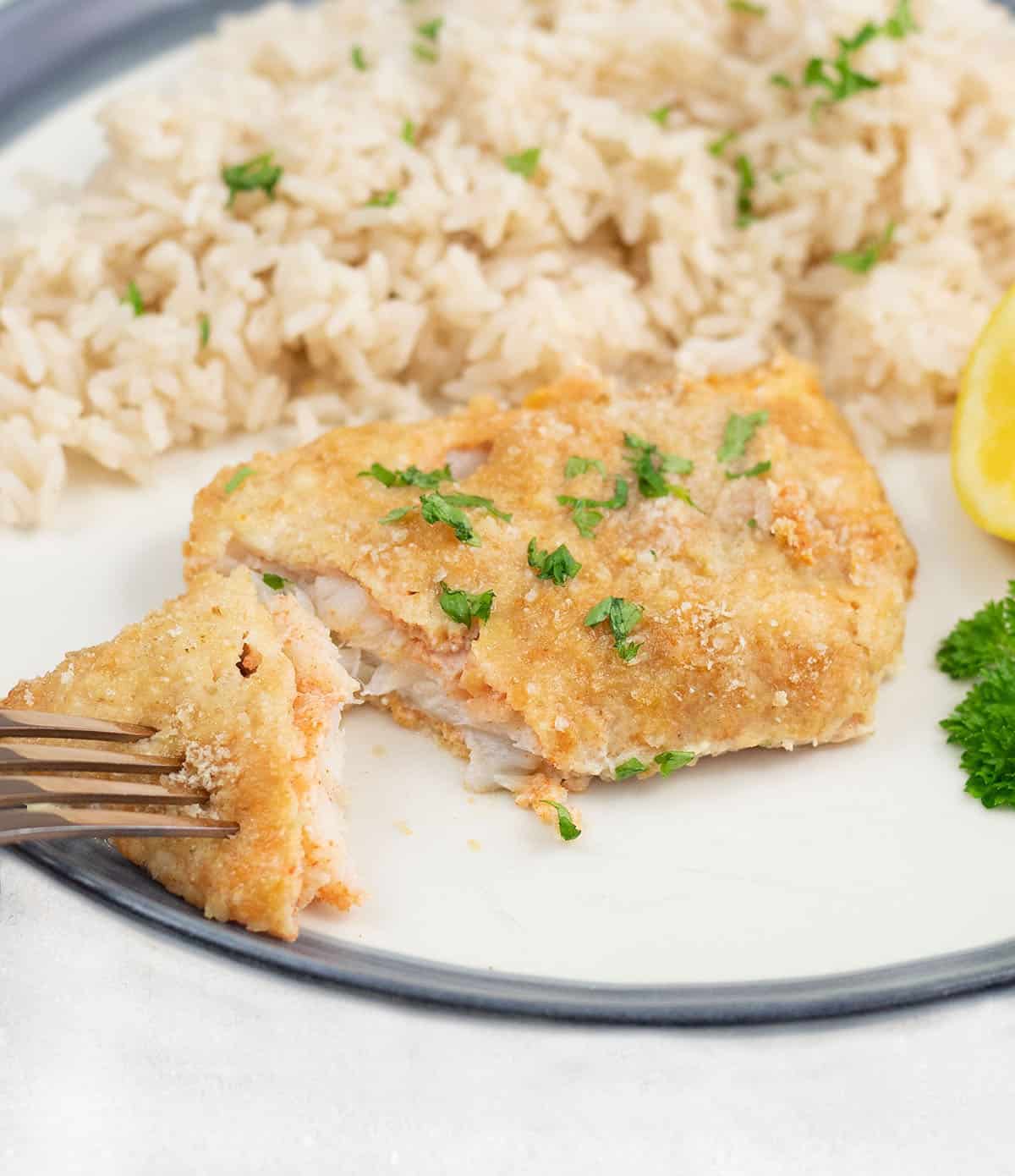 crispy baked cod with parmesan in a serving plate along with rice.