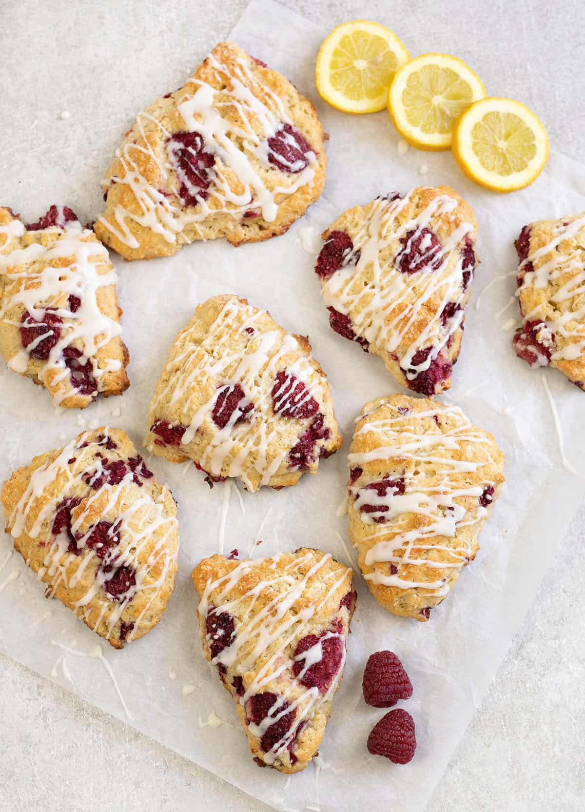 Lemon raspberry scones along with some fresh raspberries and lemon slices.