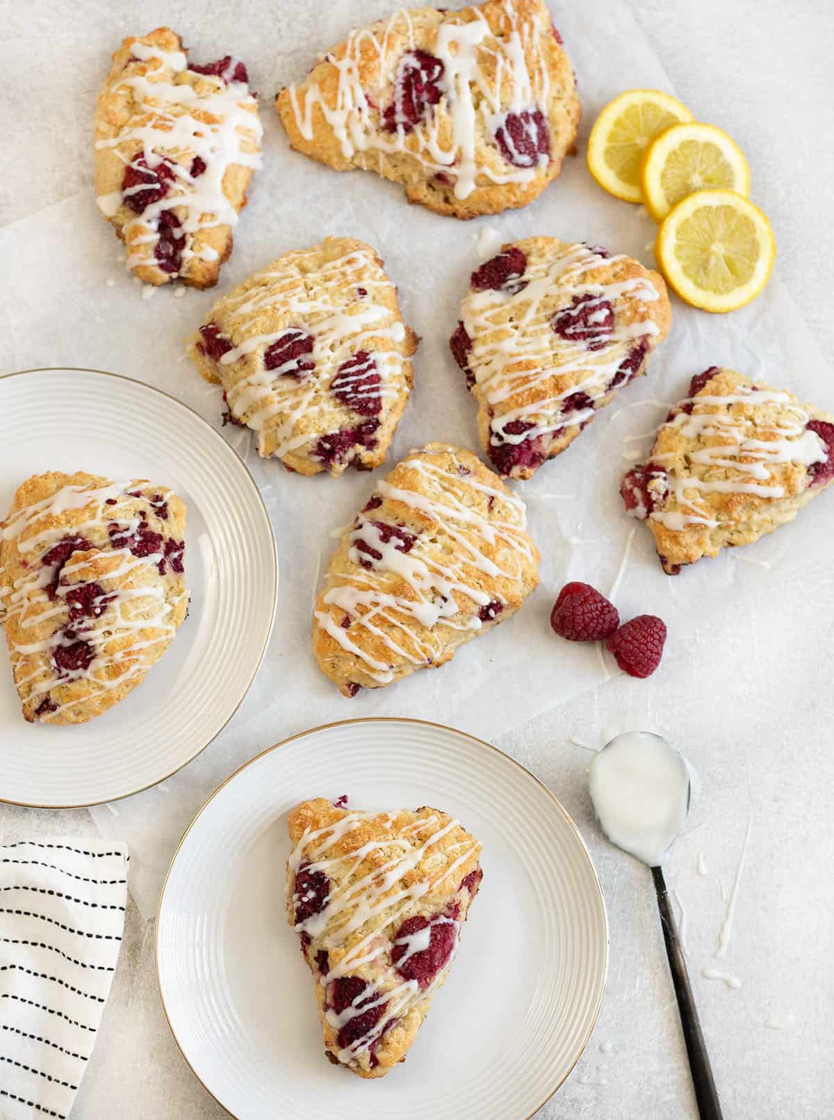 Lemon raspberry scones along with some fresh raspberries and lemon slices.