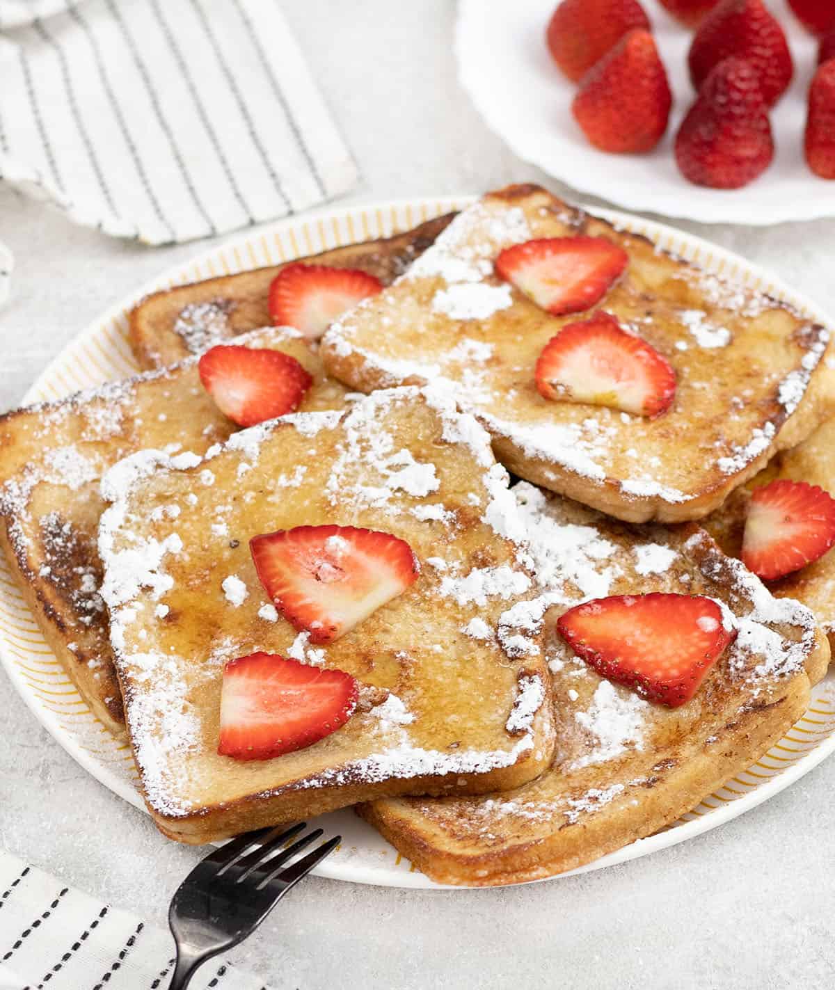 Sourdough French Toast topped with strawberries and powdered sugar.