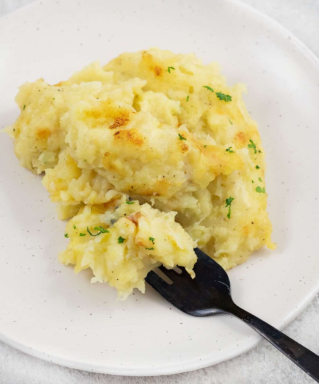 a fork full of Cheesy Garlic Mashed Potatoes.