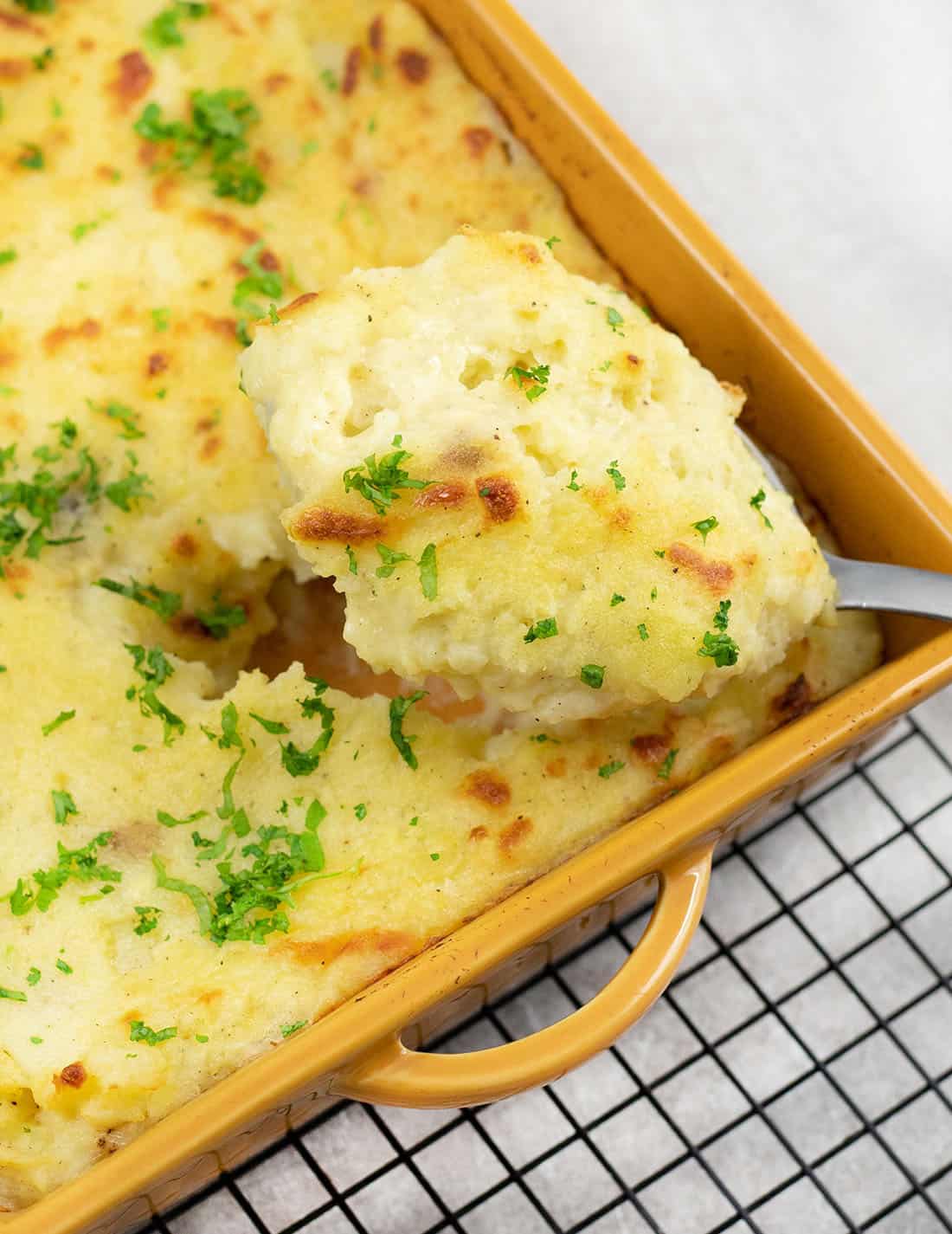 a scoop of baked cheesy garlic mashed potatoes.