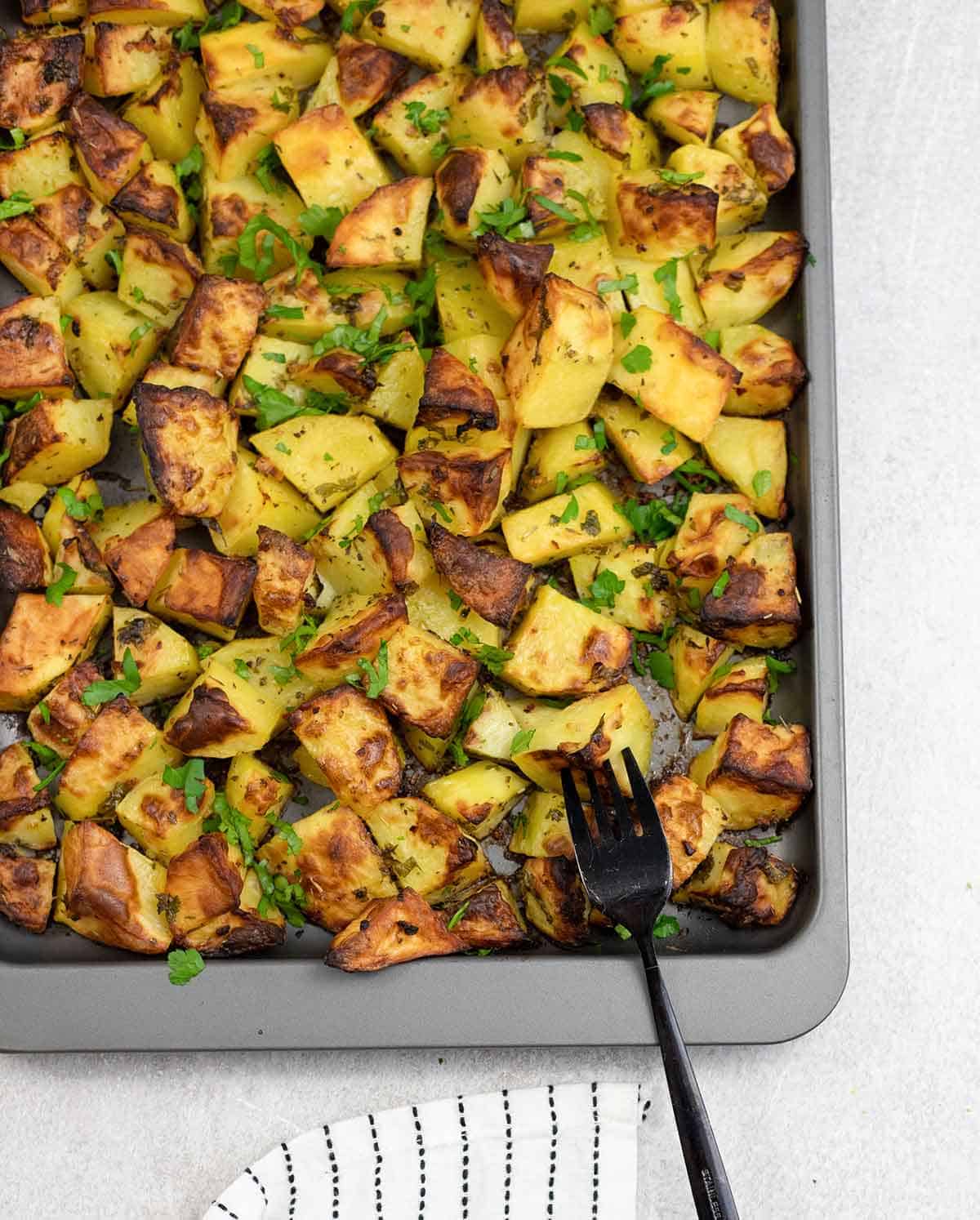 Perfectly roasted potatoes with thyme and garlic on a baking sheet.