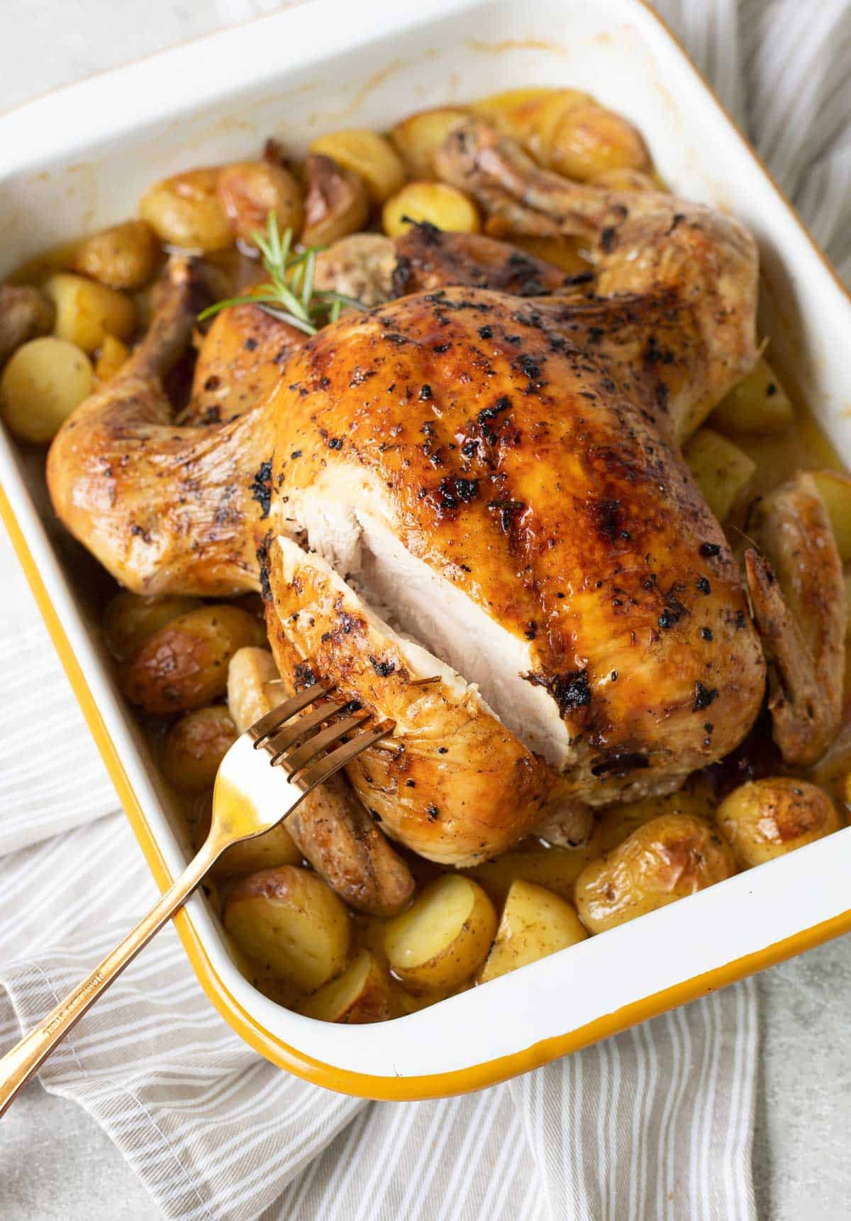 roasted chicken, potatoes and rosemary in a baking pan