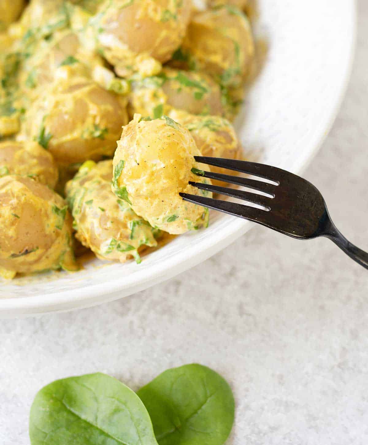 bowl full of Spicy Potato Salad Recipe and Spinach and fork