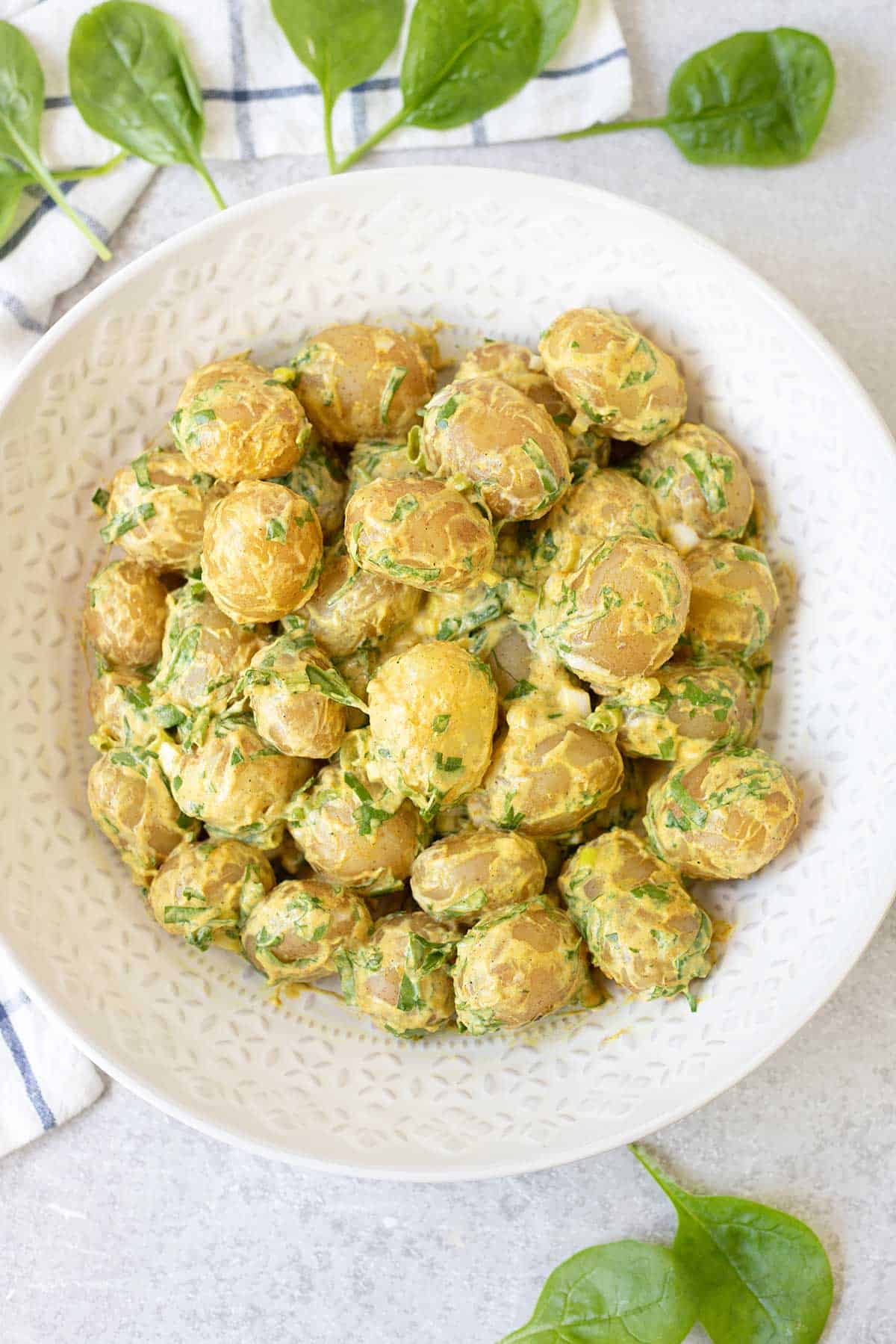 a big salad bowl full of Spicy Potato Salad and Spinach