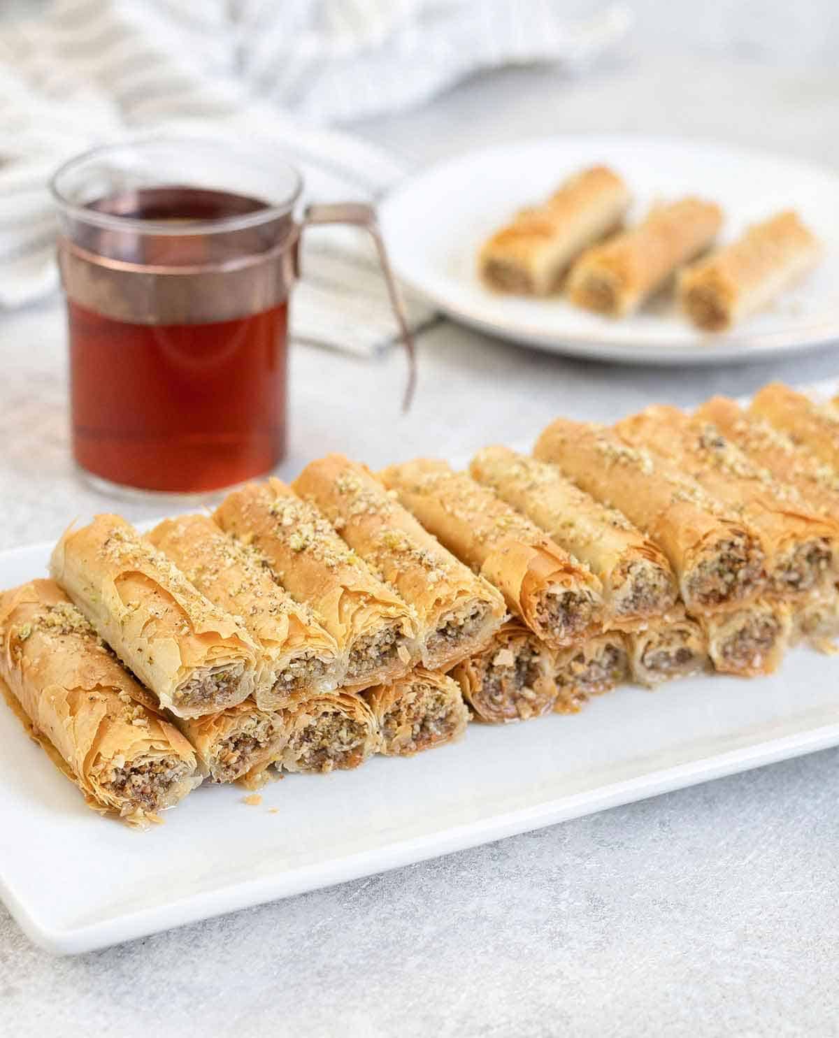 a plate full of Baklava Rolls and a cup of tea.