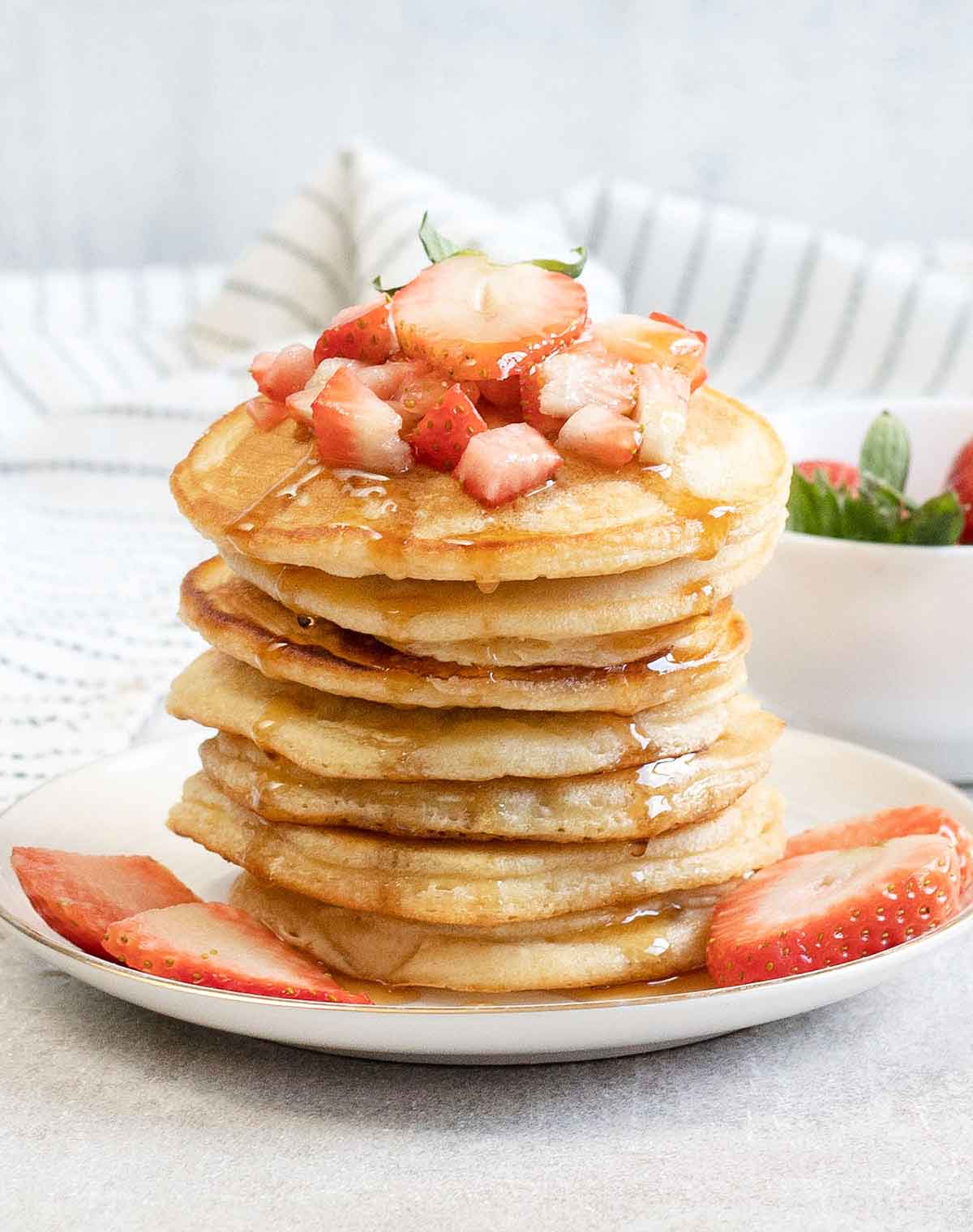 a pile of Oat Milk Pancakes and strawberries in a plate