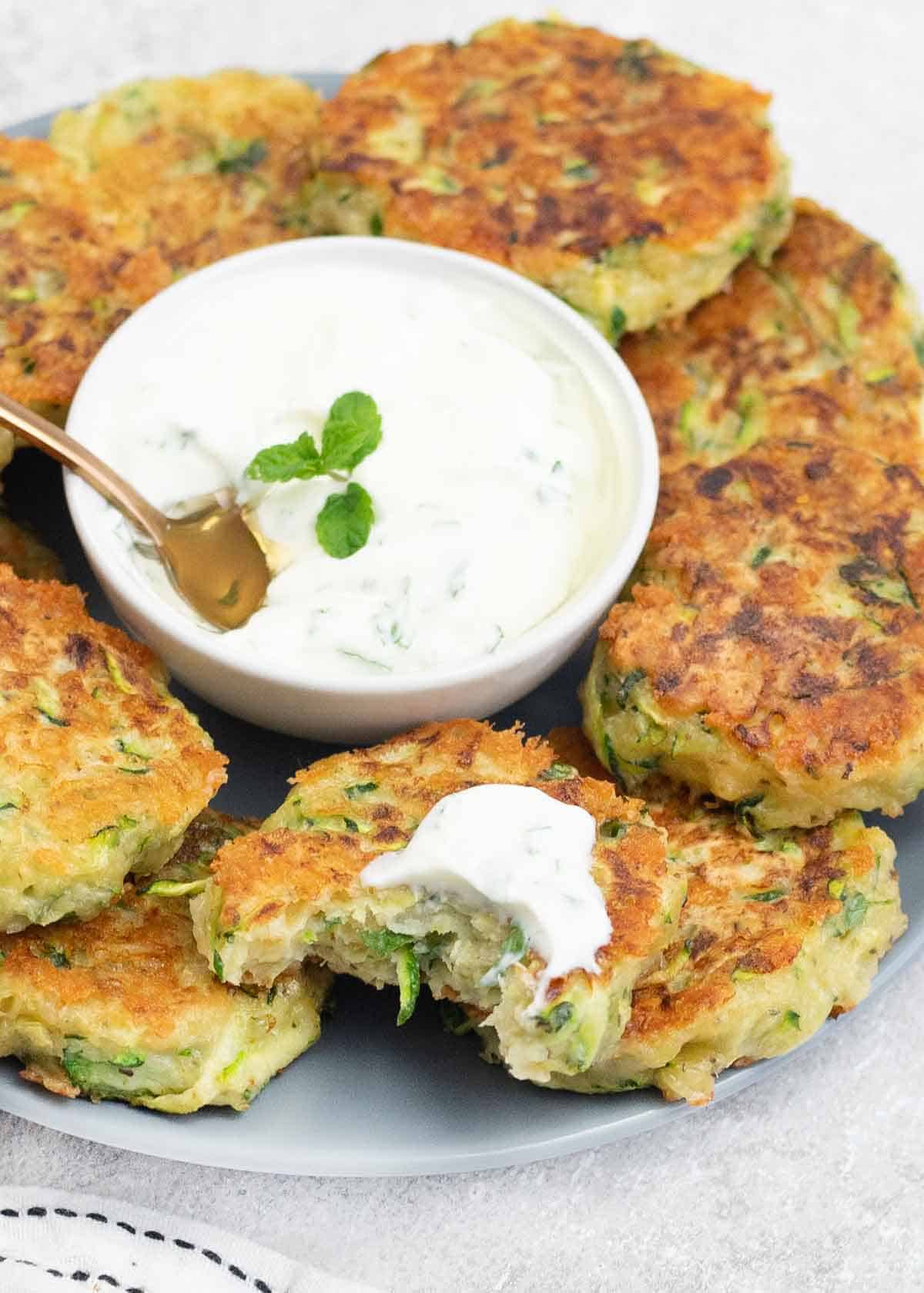 one of the Cheesy Courgette Fritters dipped in the yogurt sauce