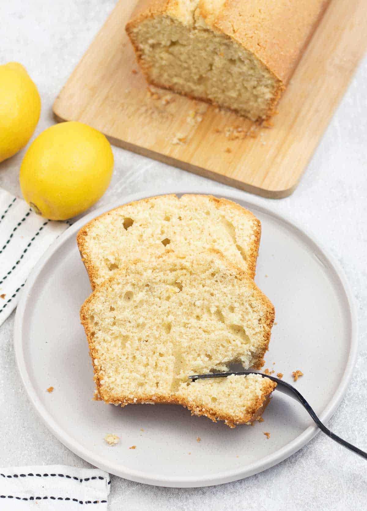 2 slices of Madeira Loaf Cake in a plate and lemon on the background