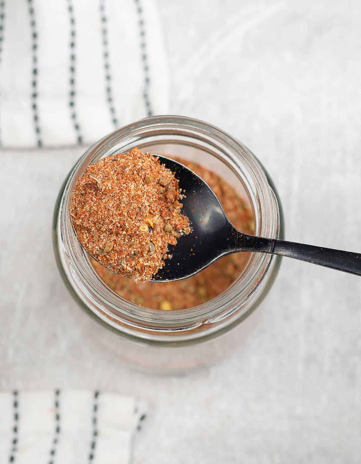 taking one spoon of Meatball Seasoning from a glass jar.