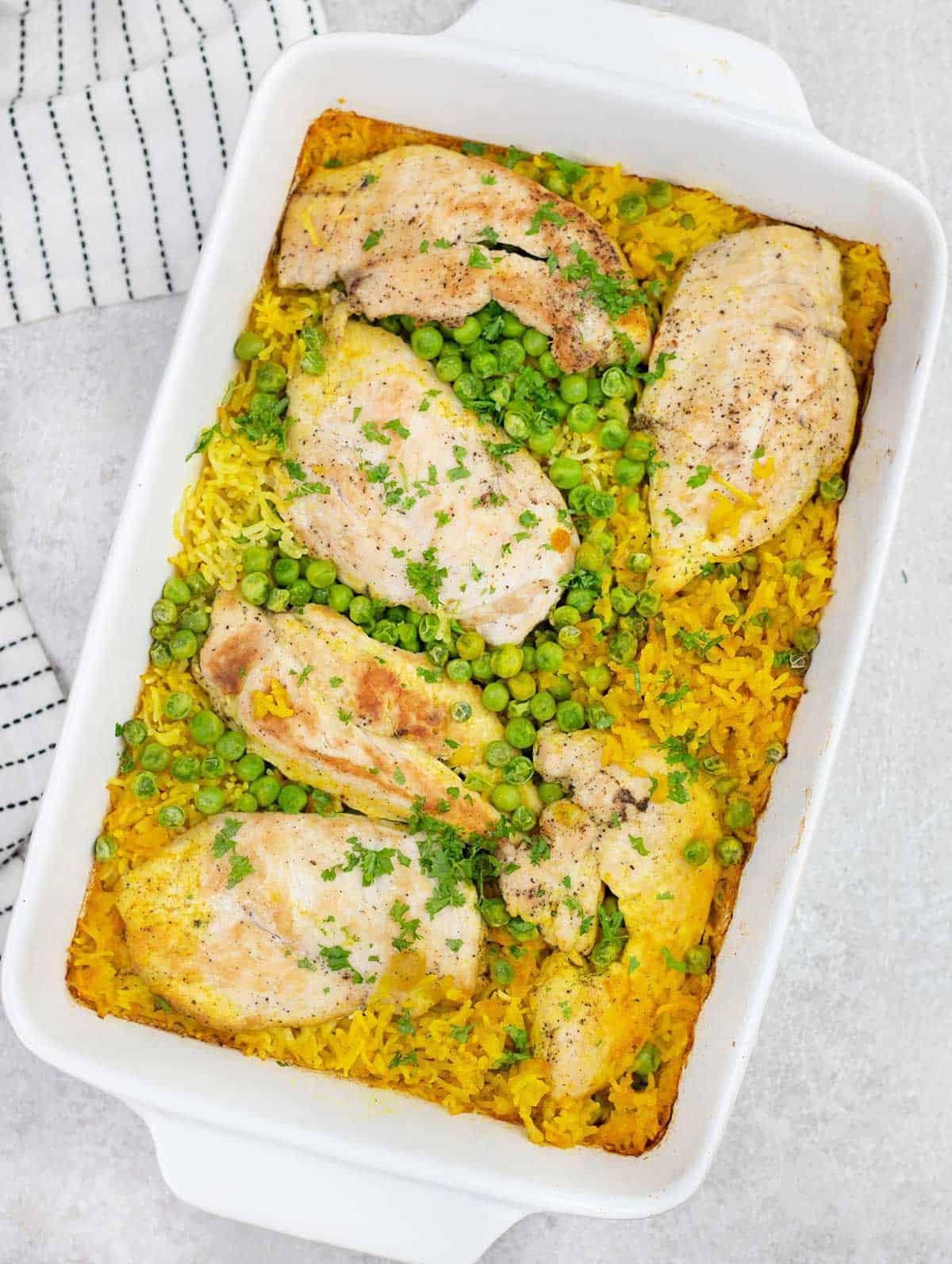 Overhead shot of a slice of chicken and some yellow rice and peas.