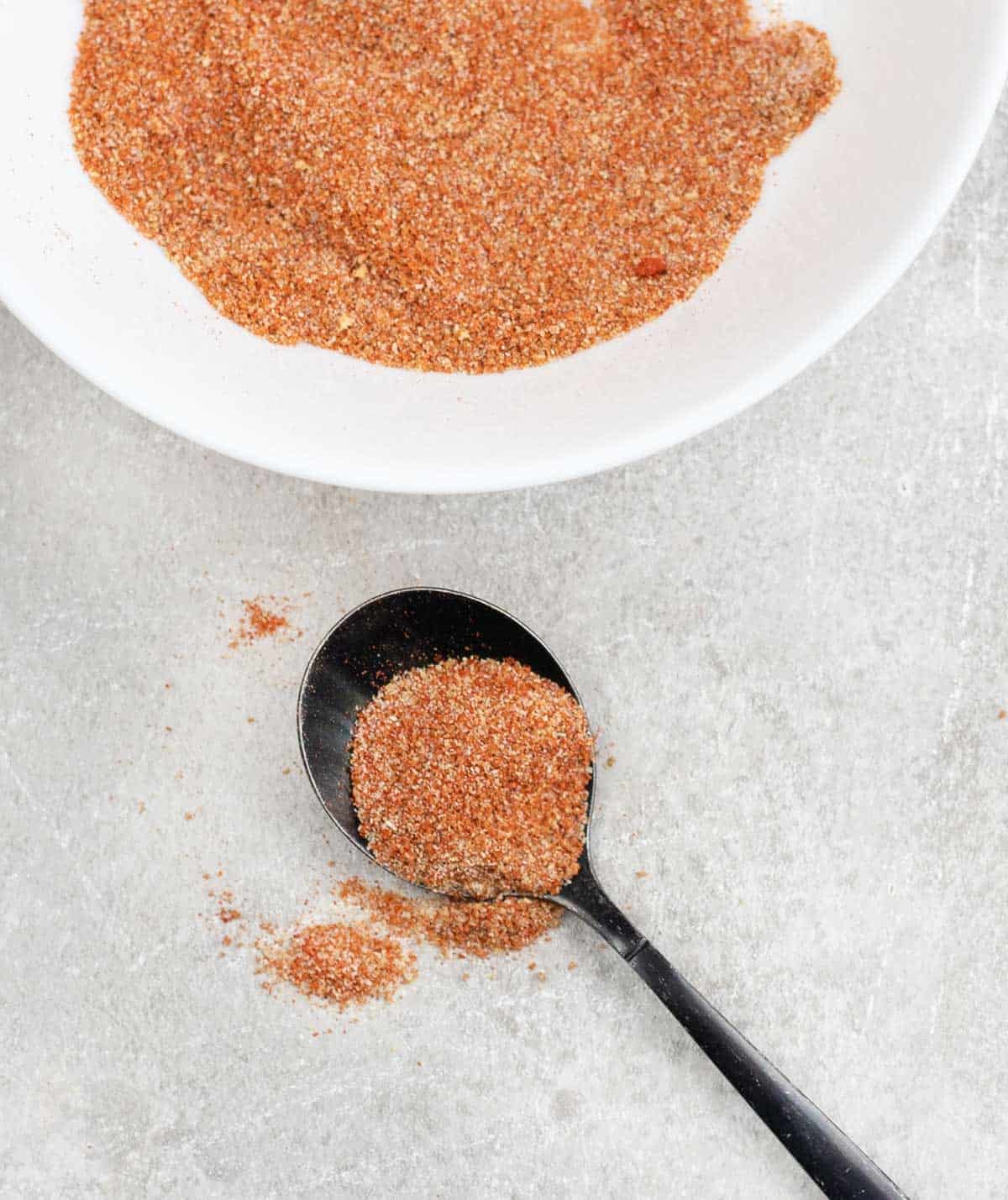 Enchilada seasonings in a plate and sprinkled on the table.