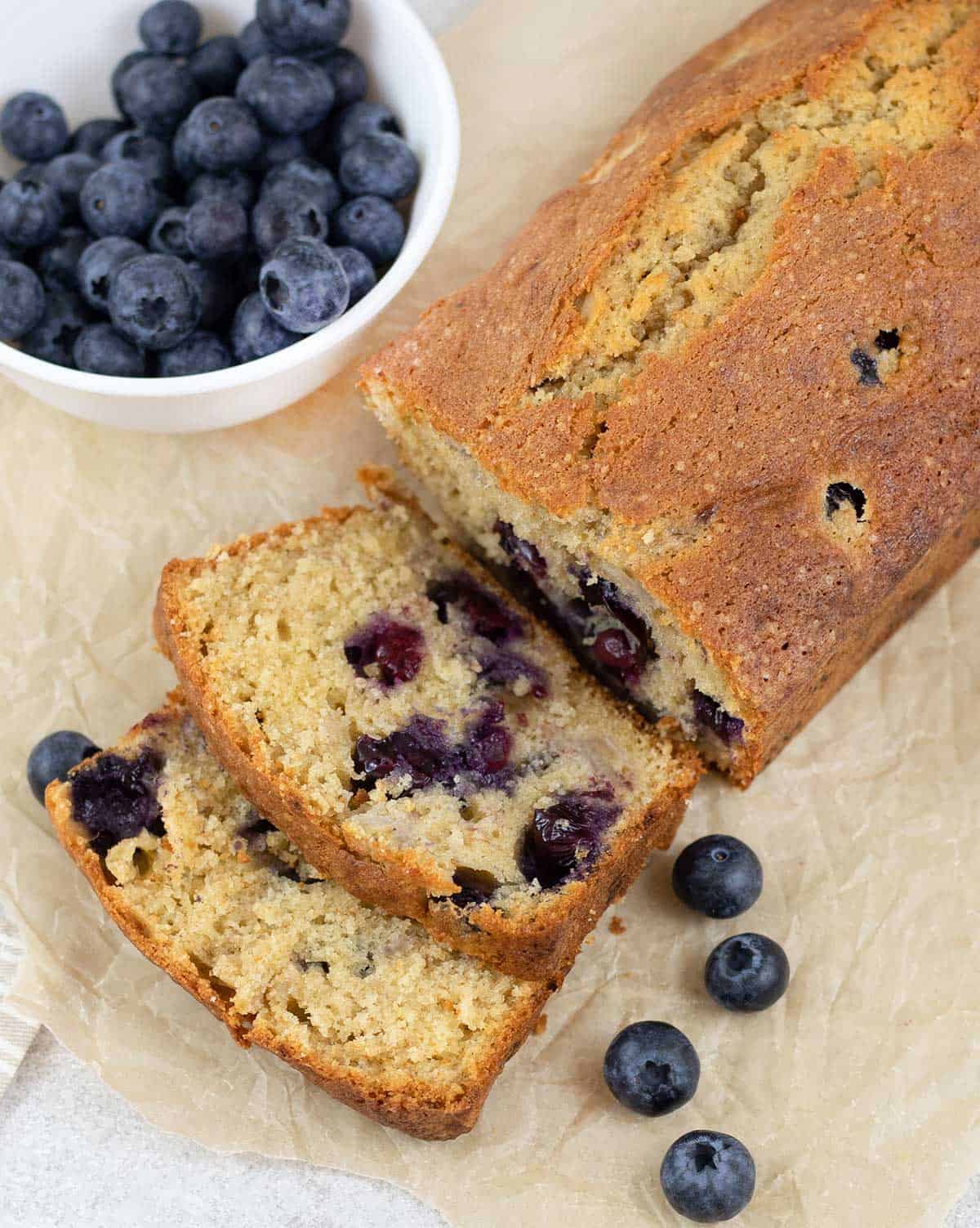 Cut the Blueberry Banana Bread and some fresh Blueberries are arround.