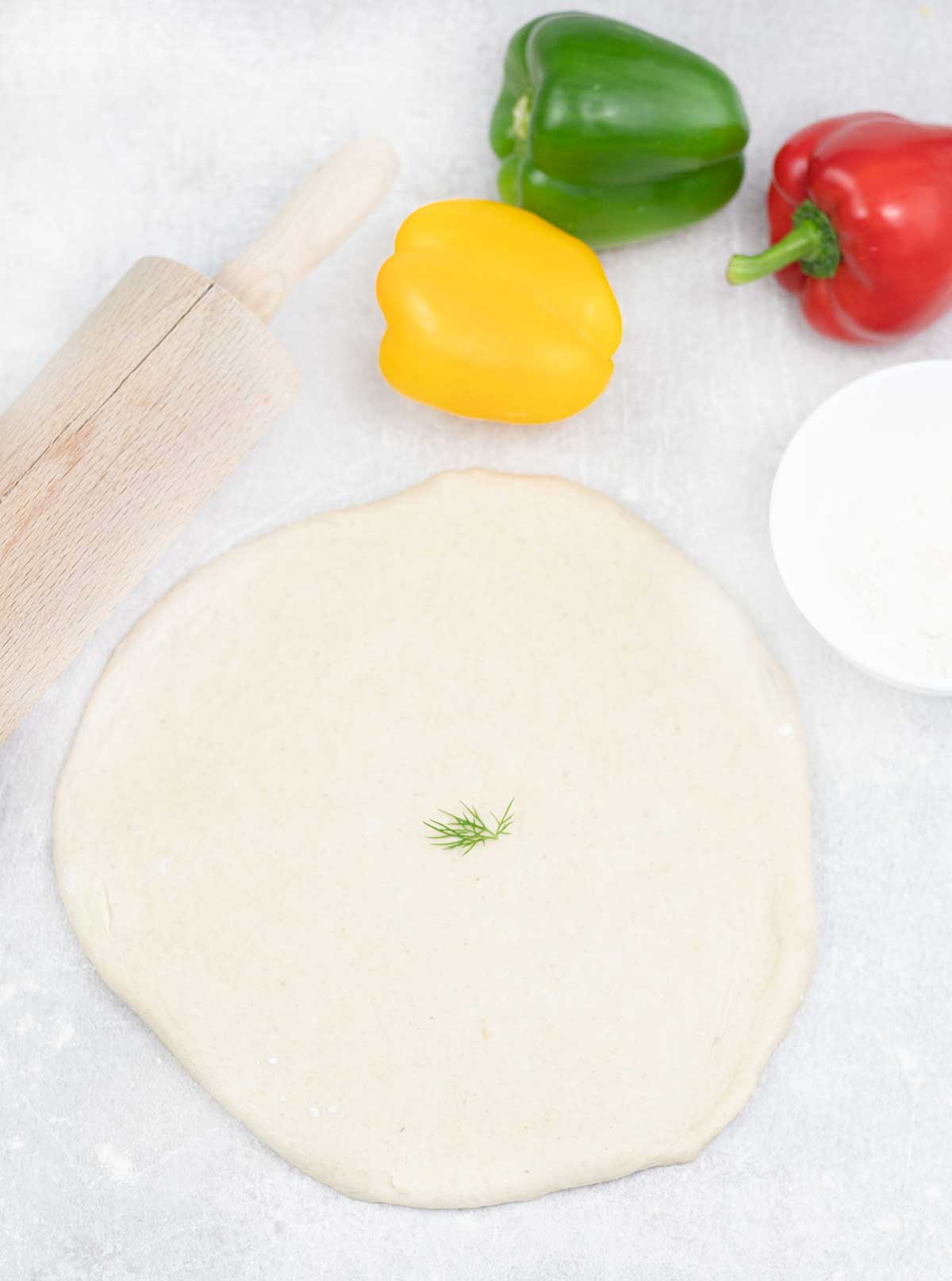 dolling out the Pizza Dough with Plain Flour and some bell pepper next to it