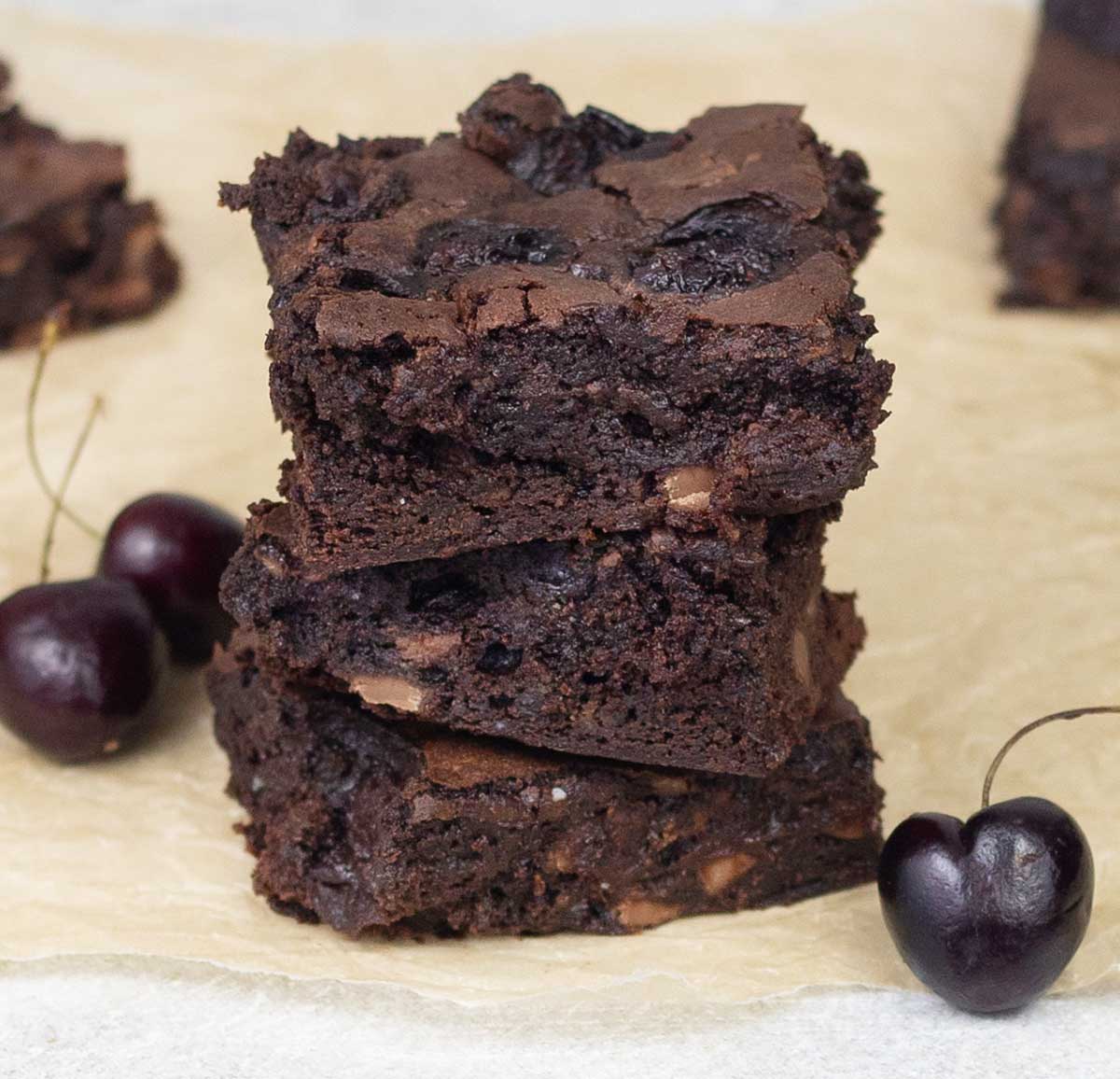 cocoa cherry brownies on top of each others and some cherries.