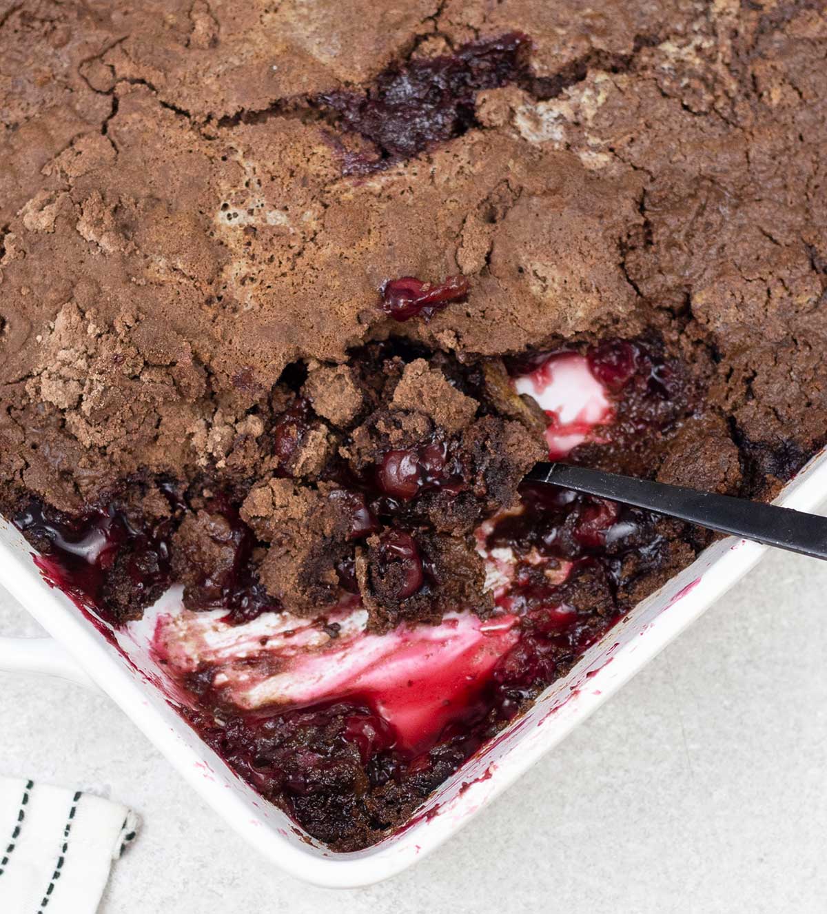 Chocolate cherry dump cake with cherry pie filling in a baking pan.