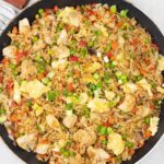 Curry fried rice with chicken and veggies are in large skillet.