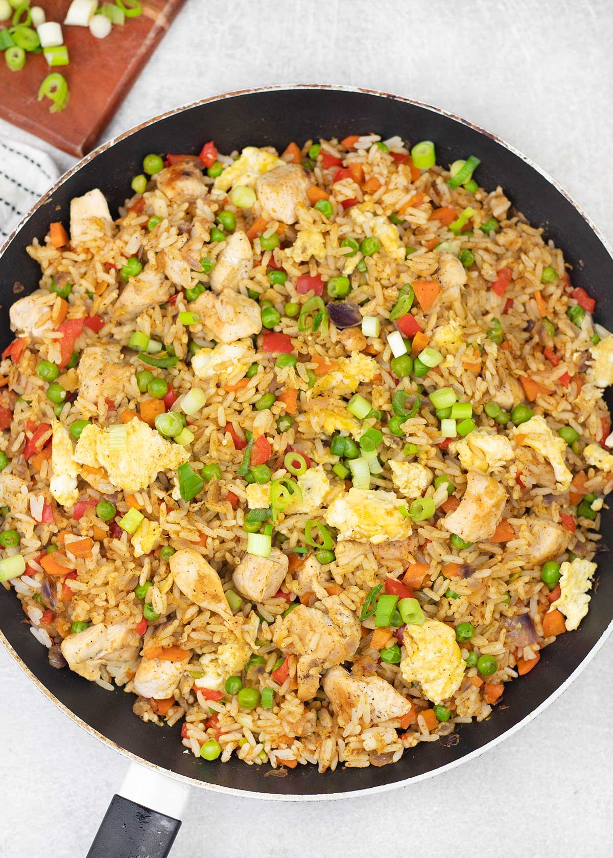 Curry fried rice with chicken and veggies are in large skillet.