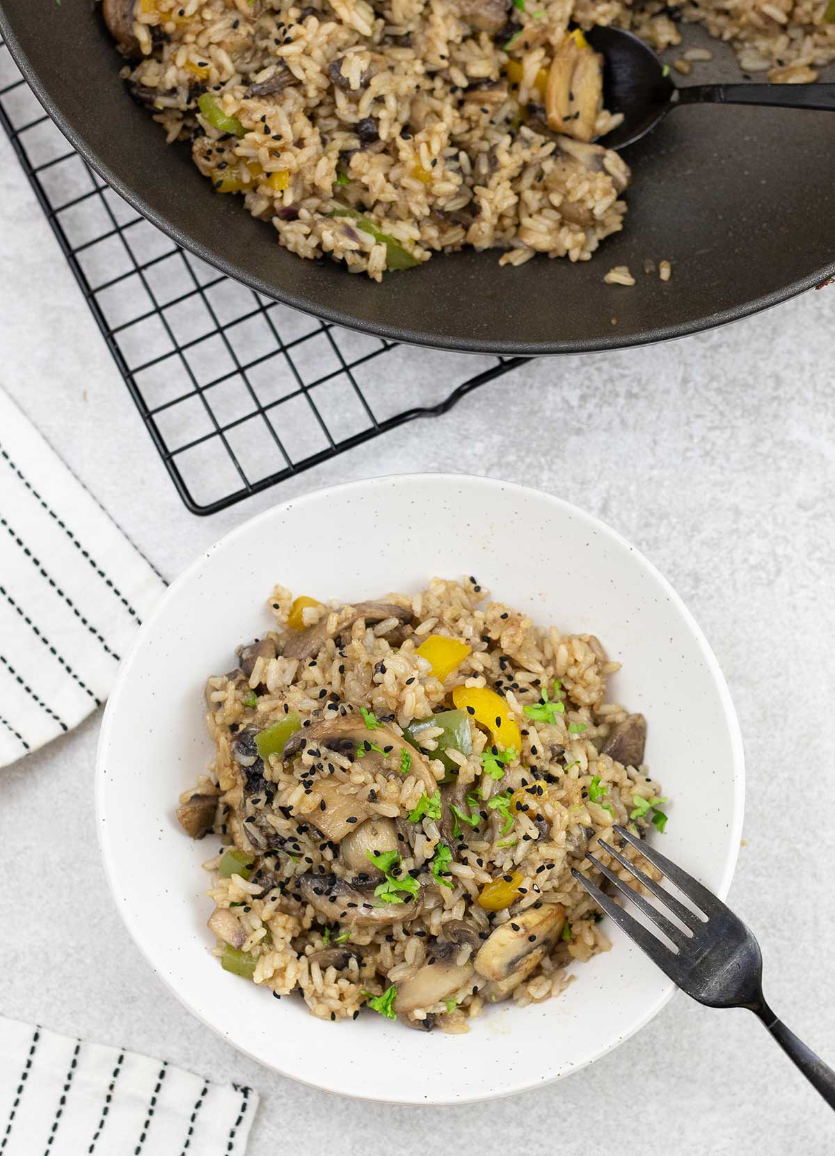 A plate full of mushroom fried rice and a pan in the background.