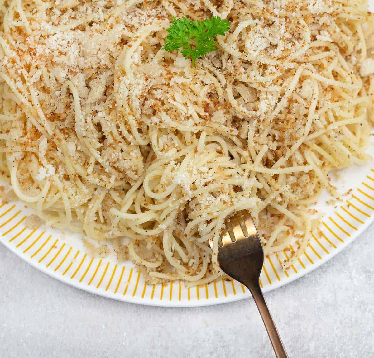 A fork full of pasta with breadcrumbs.