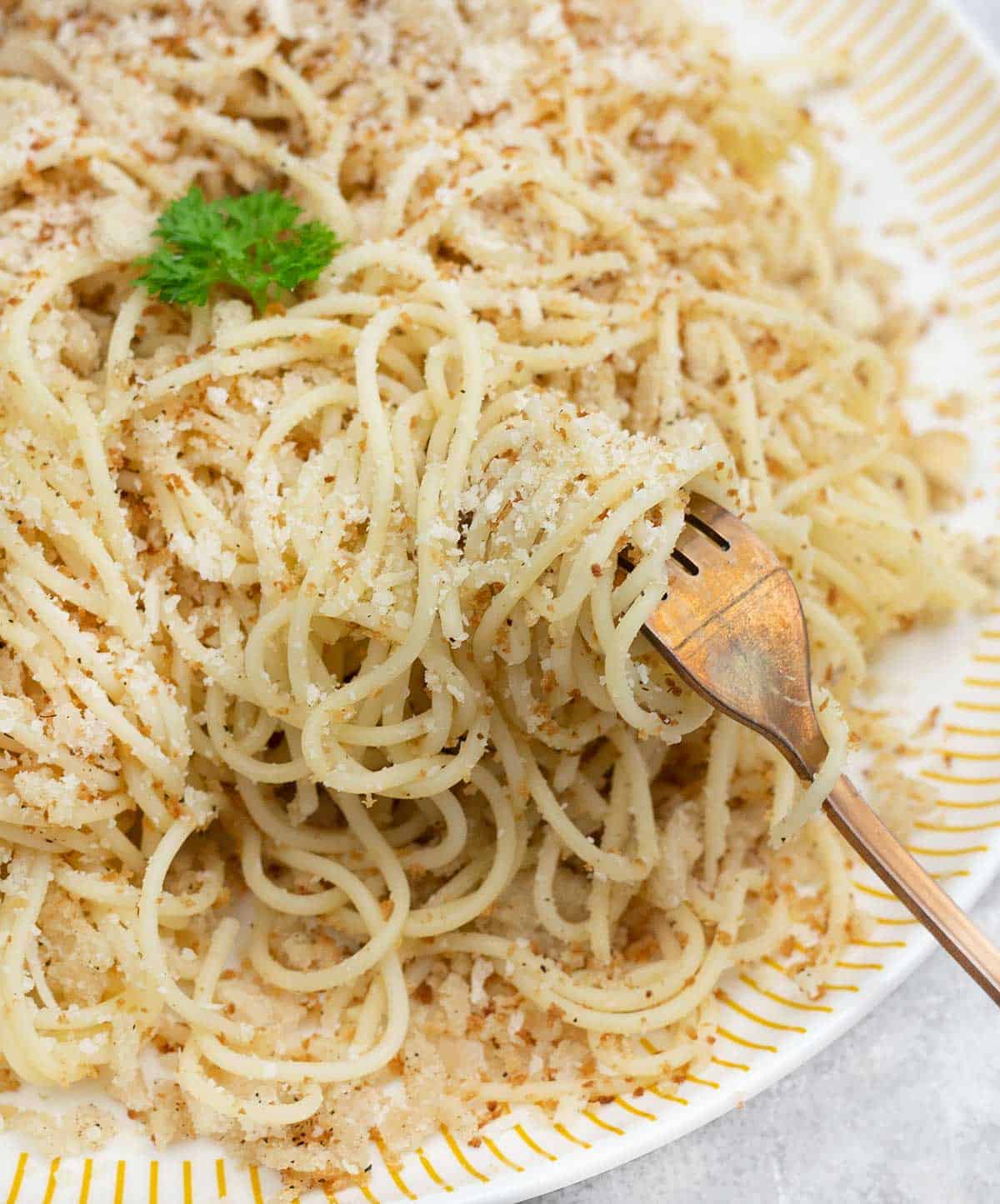 A fork full of pasta with breadcrumbs.