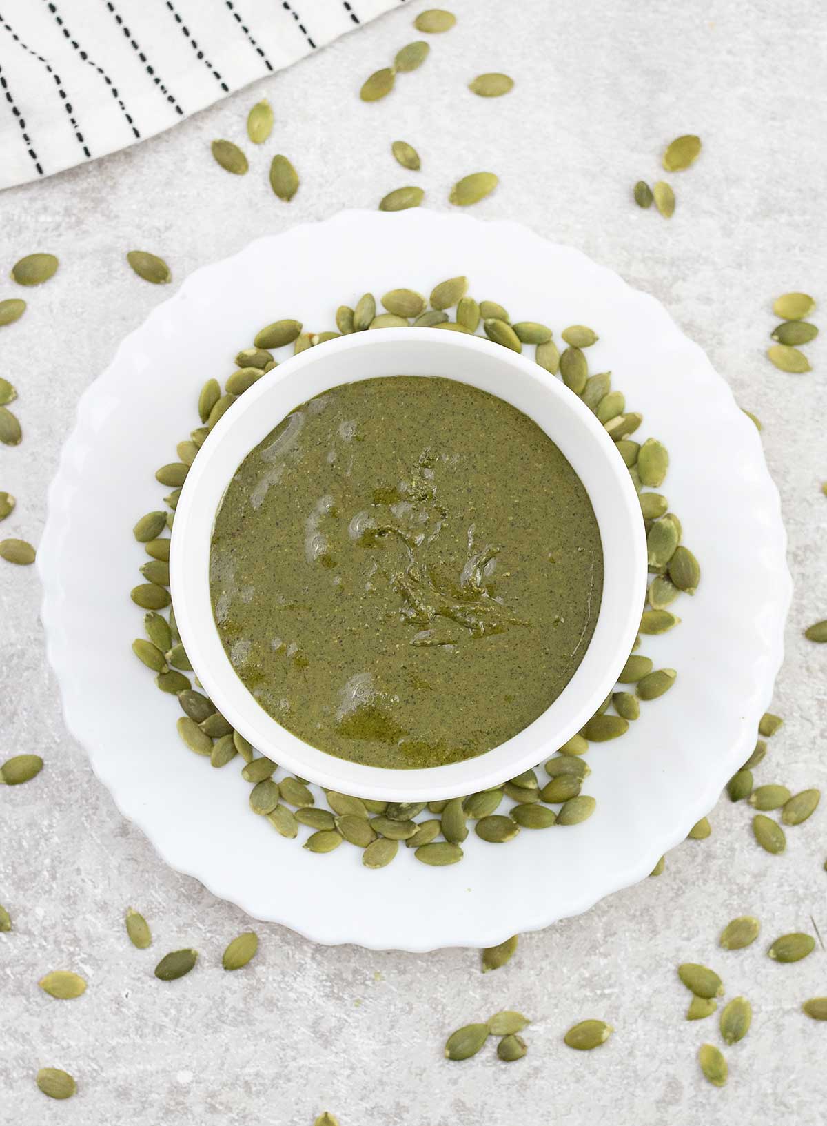 Pumpkin seed butter in a small bowl with pumpkin seeds around it.