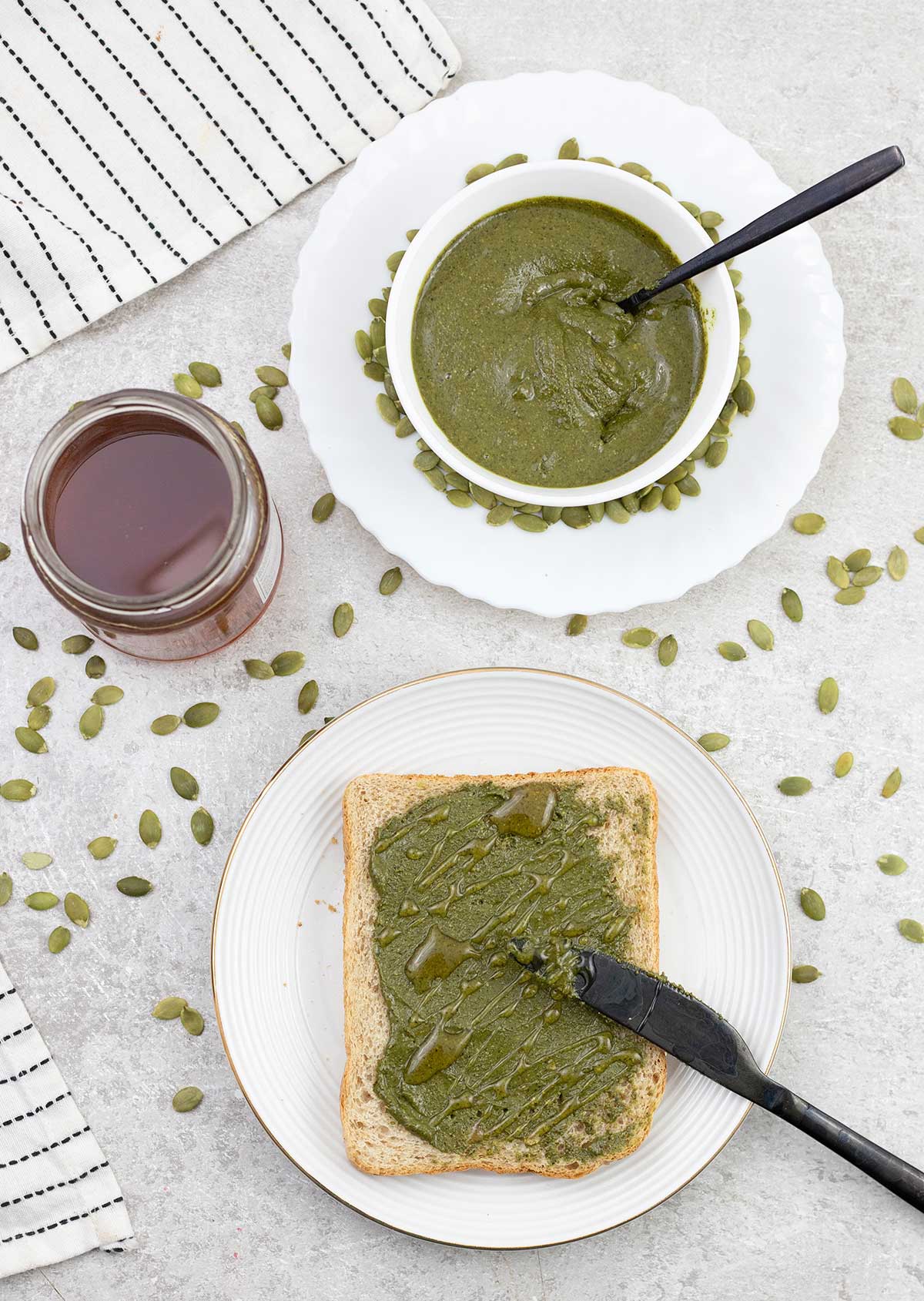 Pumpkin seed butter on toast and a glass of honey and a bowl full of pumpkin seed butter.
