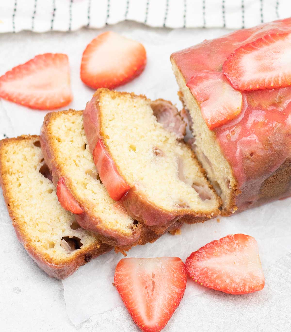 Strawberry loaf cake slices topped with some fresh strawberries glaze.