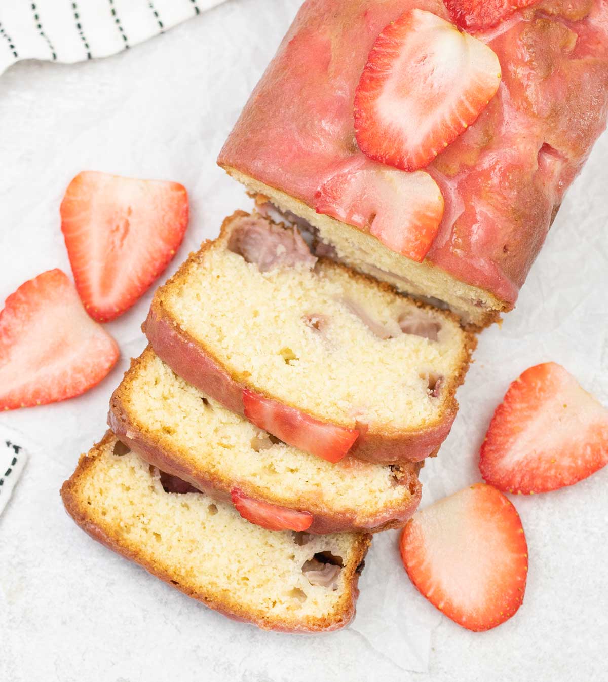 Strawberry loaf cake topped with some fresh Strawberries.