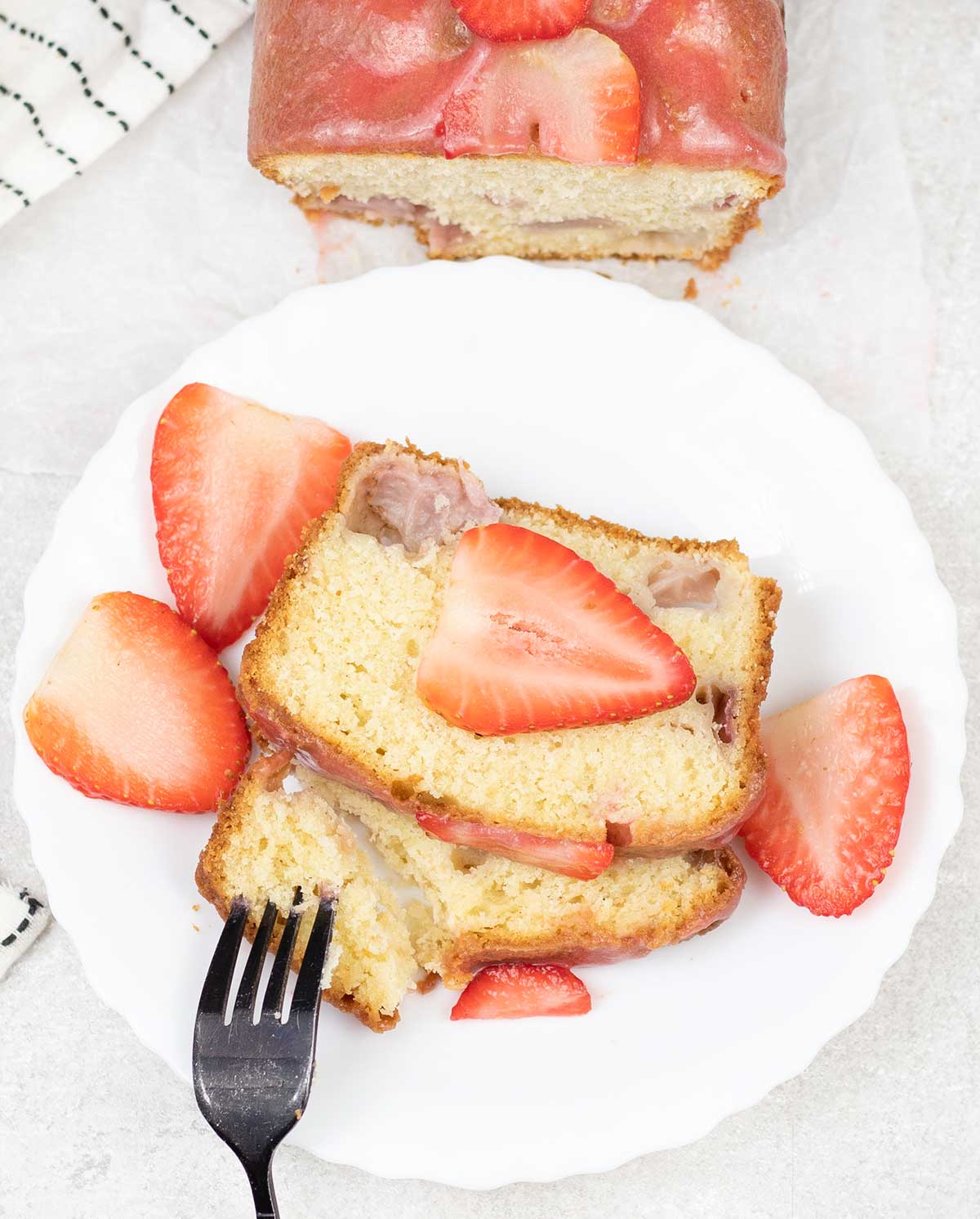 Strawberry loaf cake topped with some fresh Strawberries.