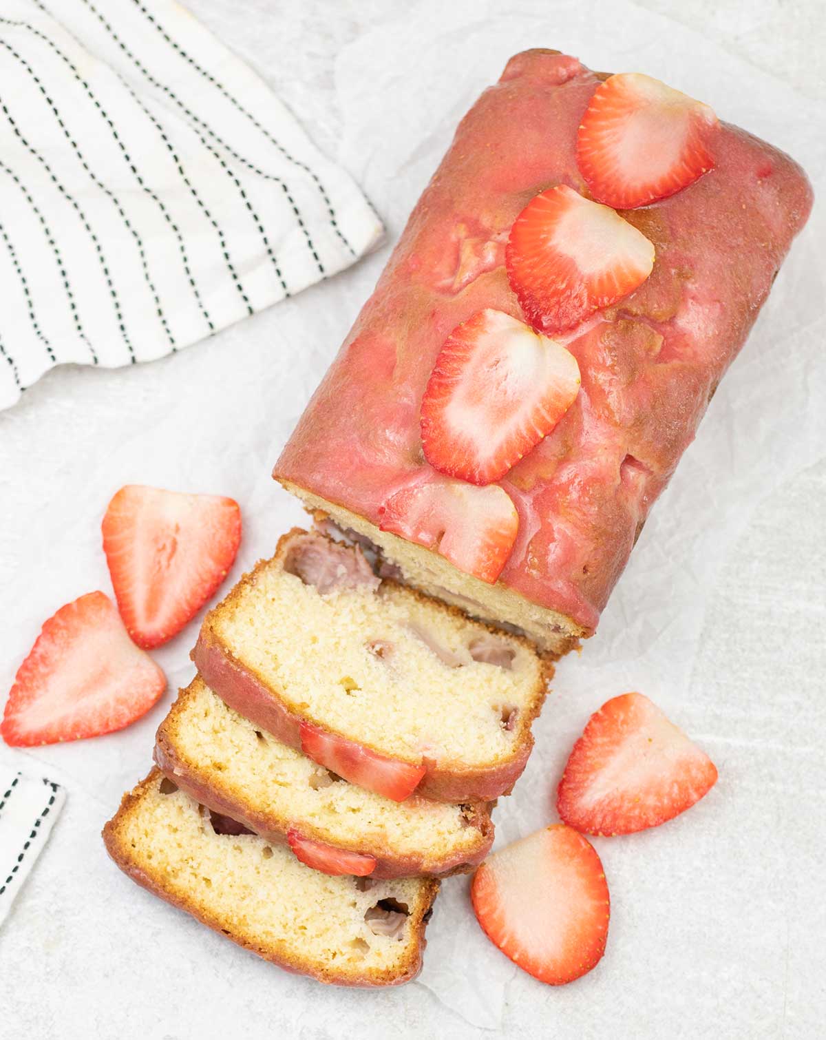 Strawberry loaf cake topped with some fresh Strawberries.