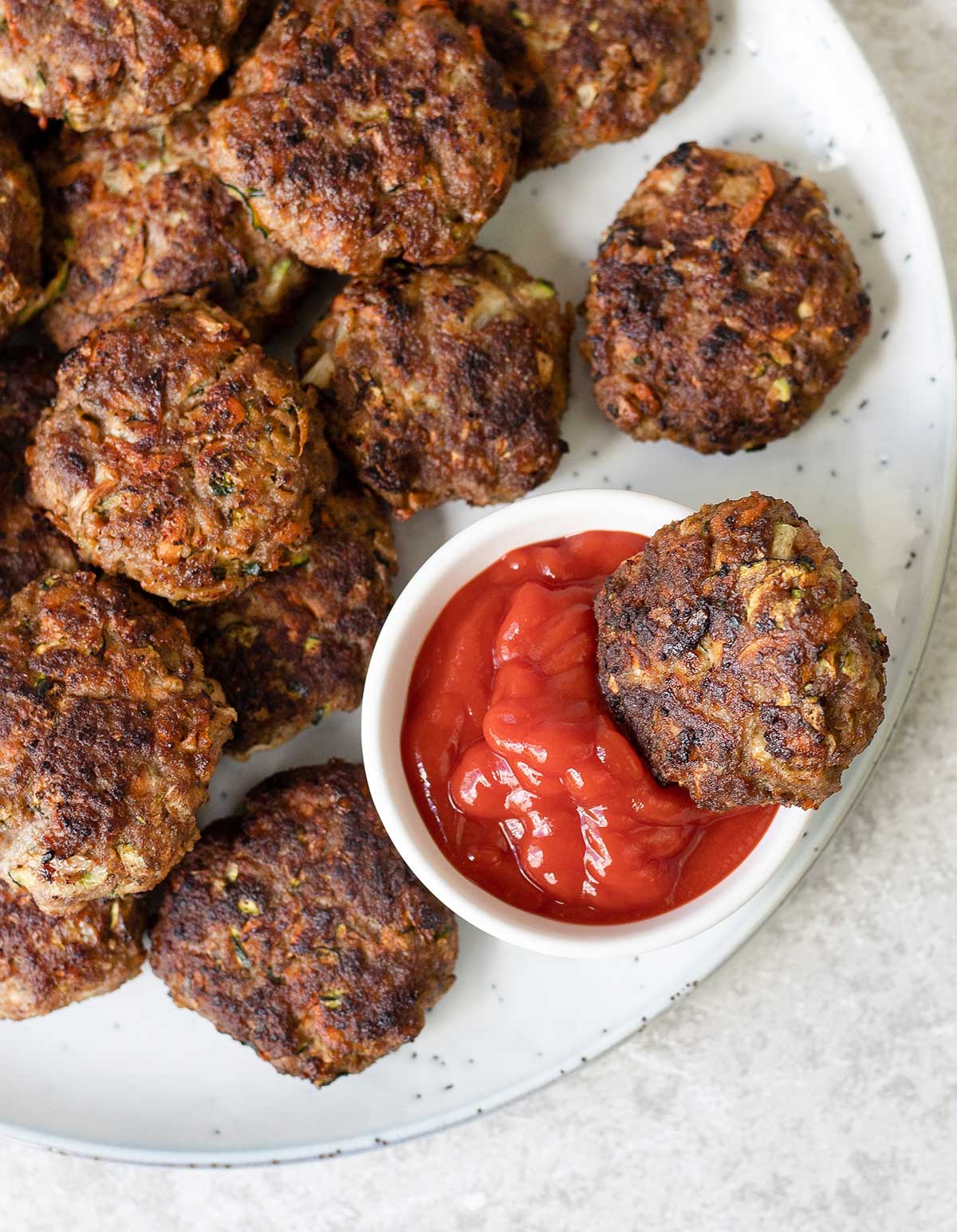 Beef and veggie Rissoles and a small bowl of ketchup.