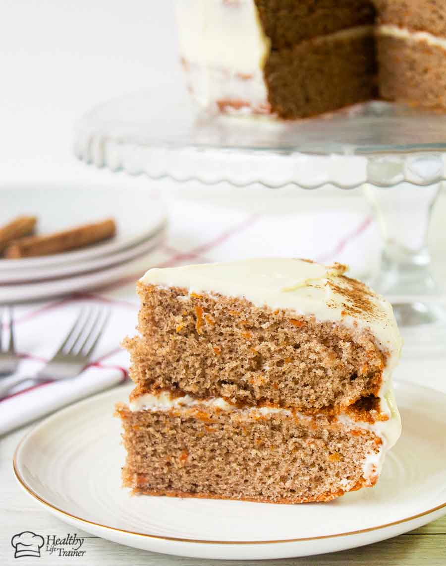 Carrot cake slice  and the whole cake is in the background.