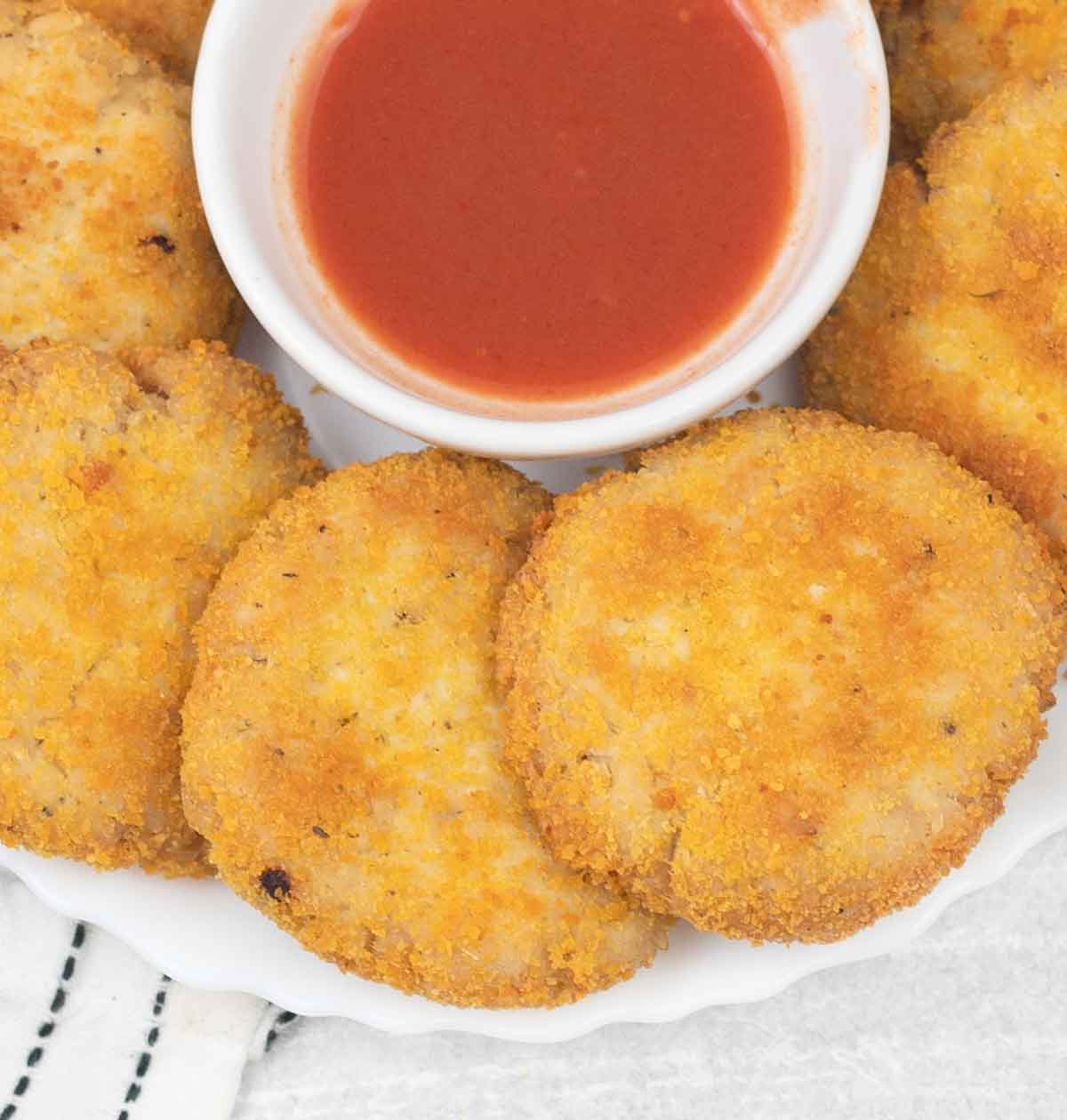 Crispy chicken patties and a small bowl of hot sauce.